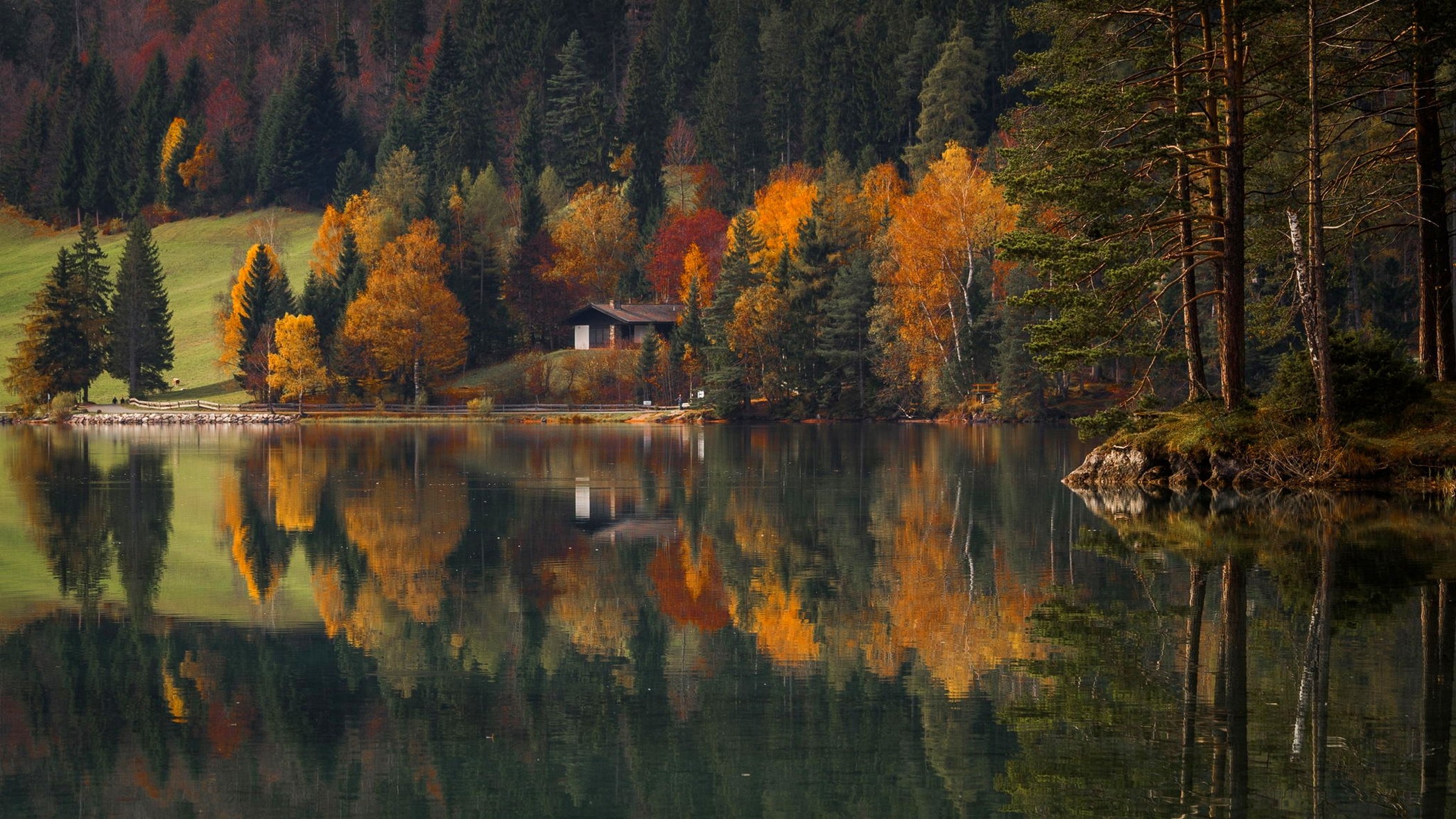 Autumn forest reflected in a calm lake with a house HD Wallpaper