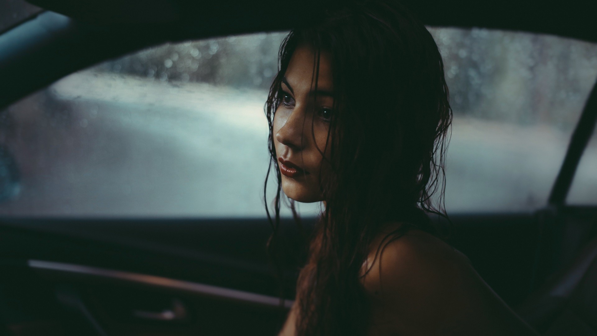 Woman with wet hair looking out a car window HD Wallpaper