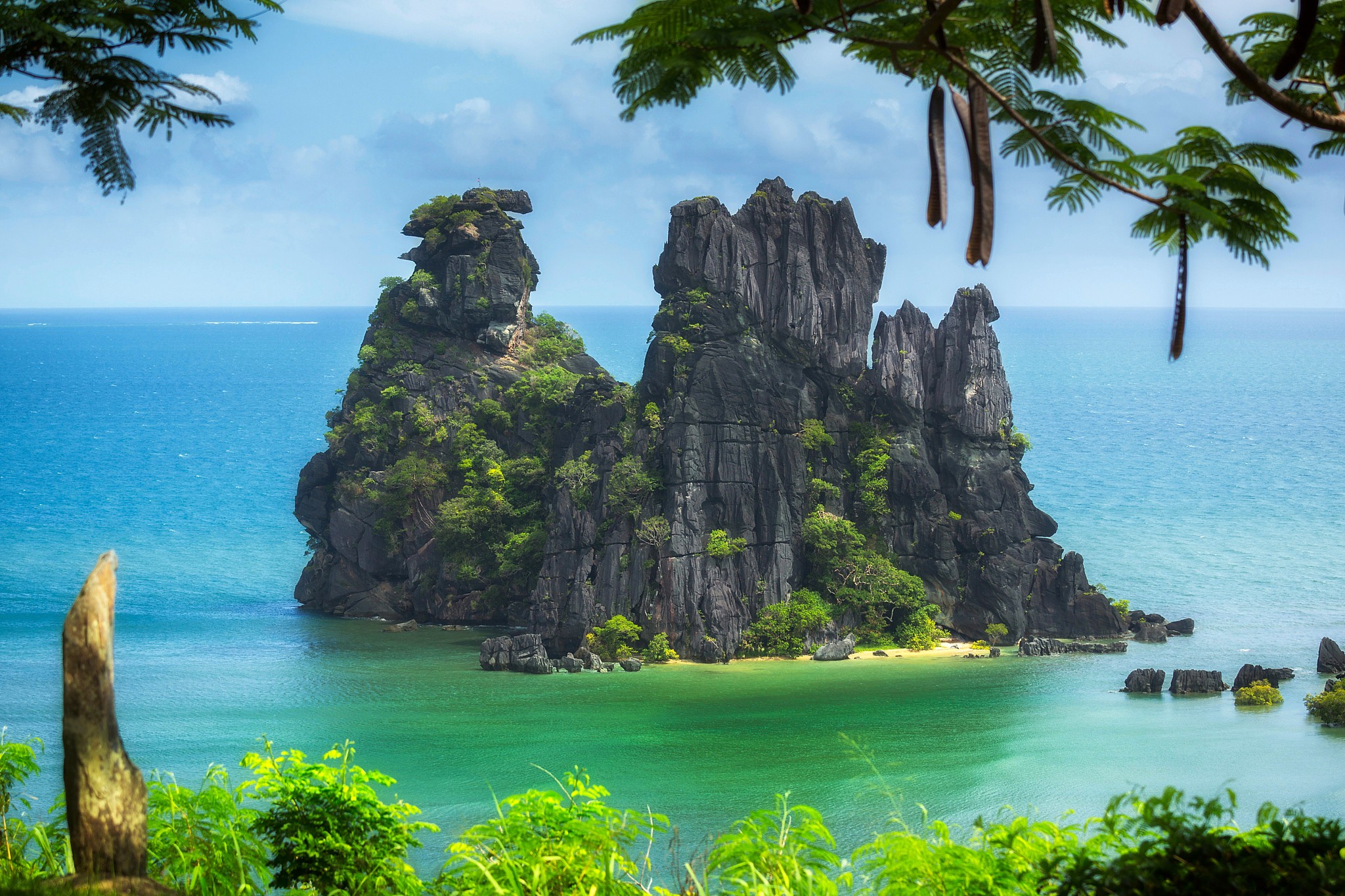 Jagged rock formations rise from the turquoise sea HD Wallpaper