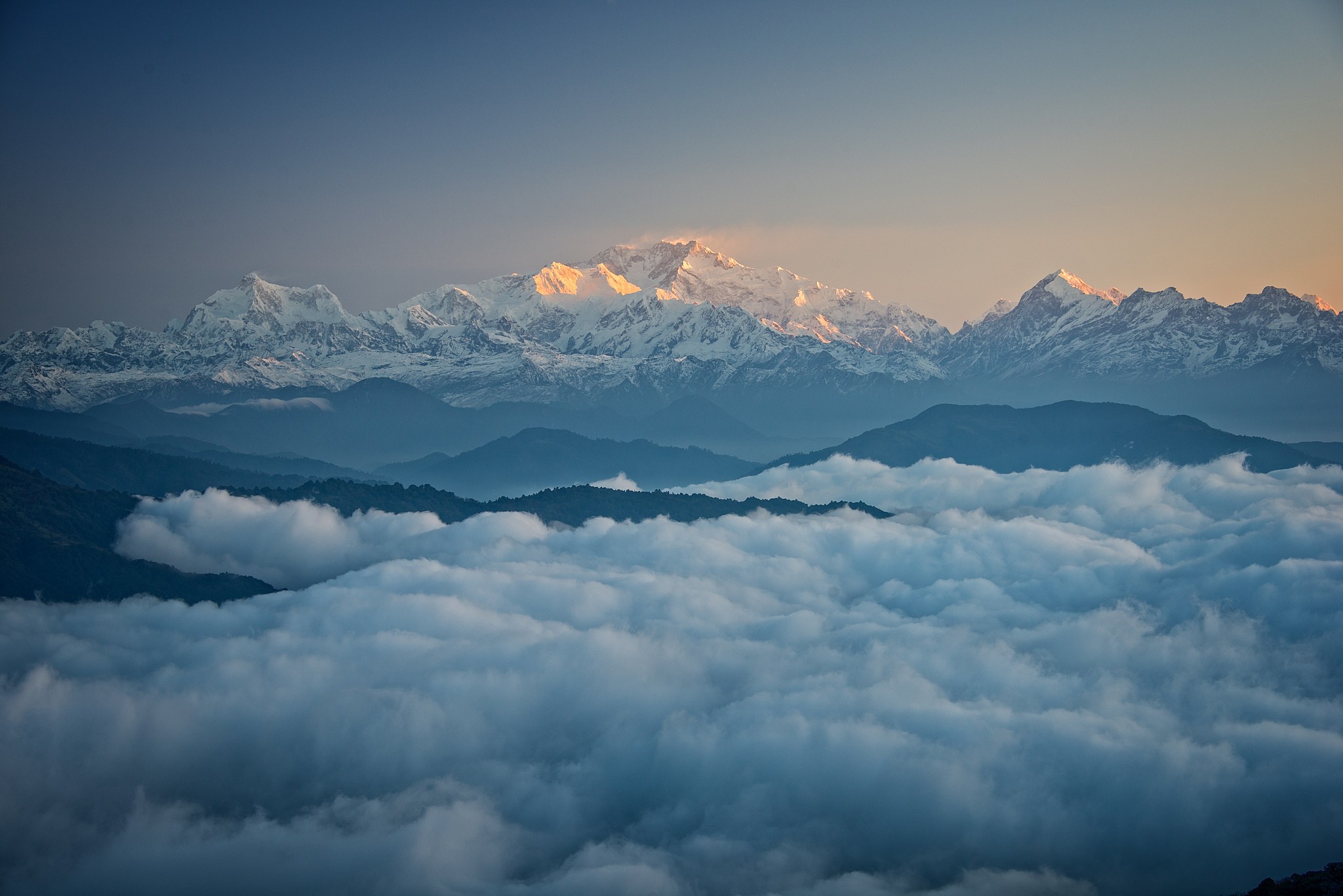 Snowy mountain peaks above clouds at sunset HD Wallpaper