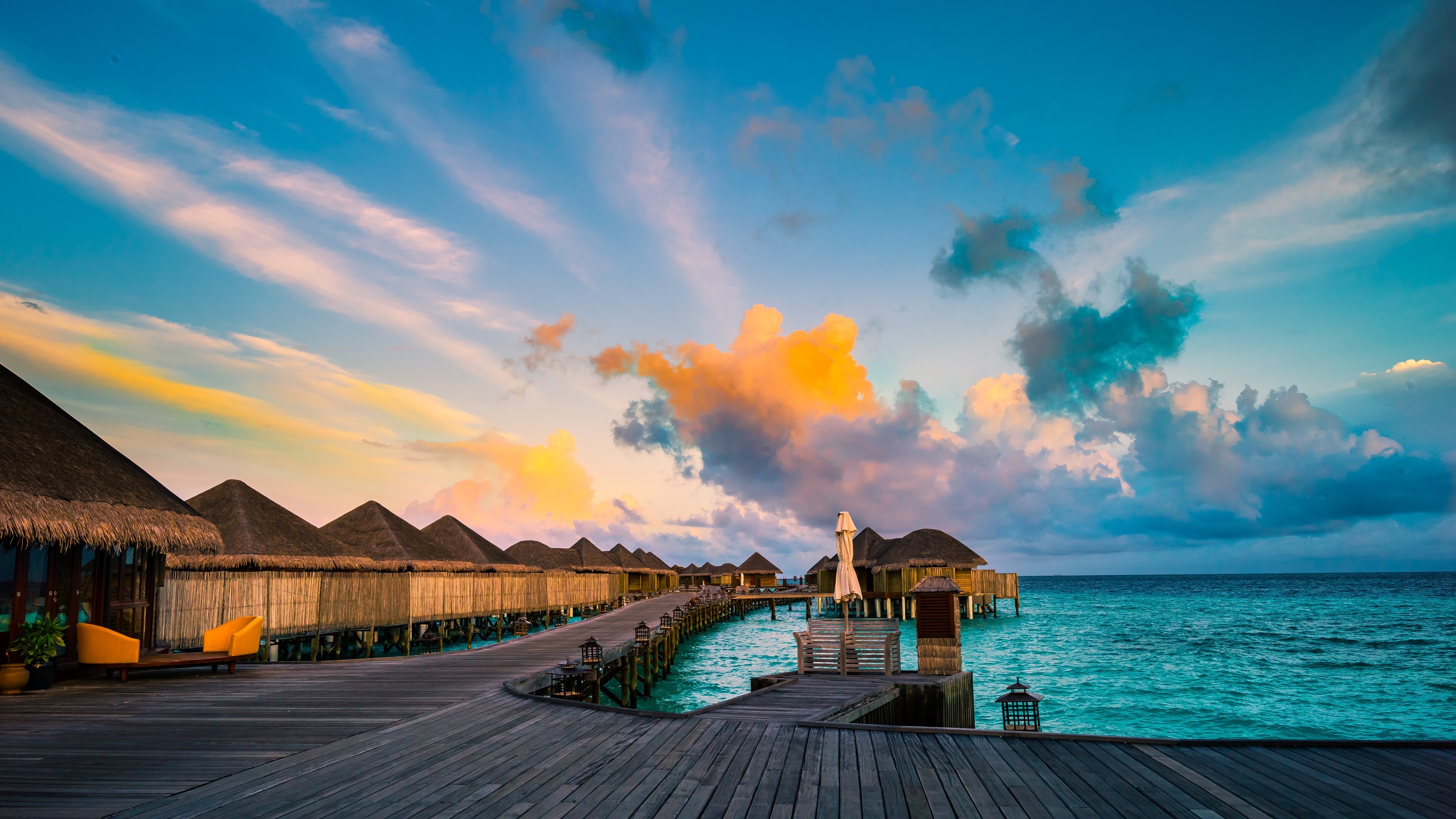 Sunset over a tropical resort with overwater bungalows HD Wallpaper