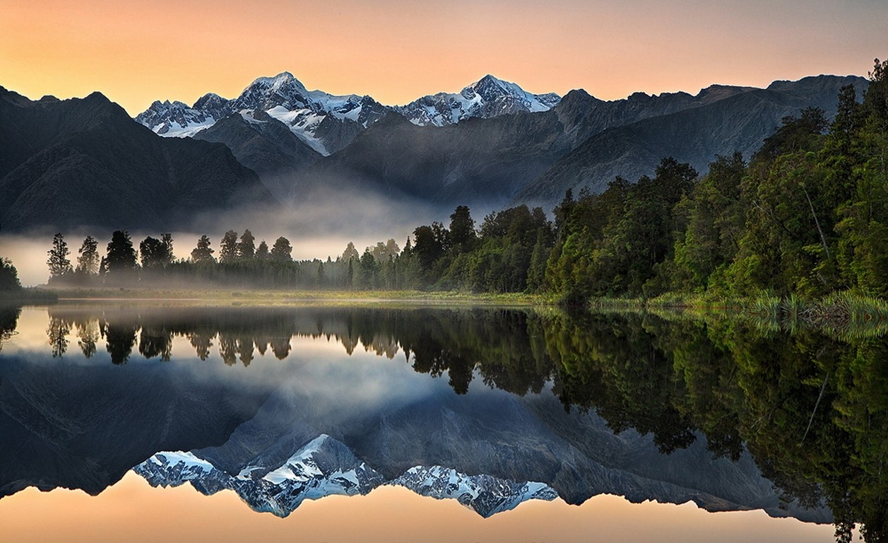 Snowy mountain peaks reflected in a misty lake in New Zealand HD Wallpaper