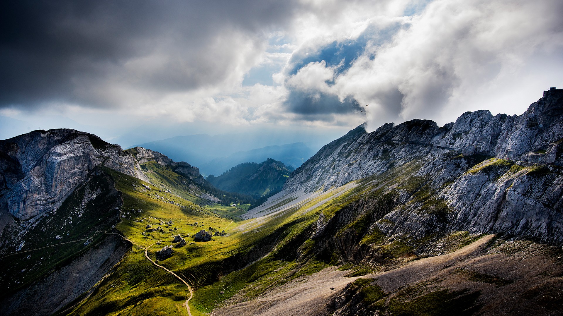 Dramatic mountain landscape with clouds and a winding path HD Wallpaper