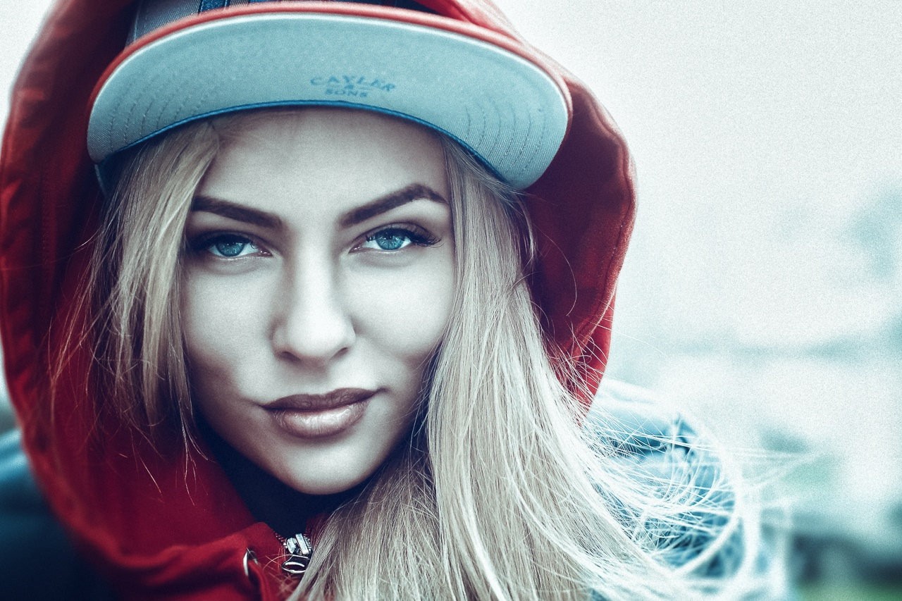 Woman with blonde hair wearing a red hoodie and a cap HD Wallpaper