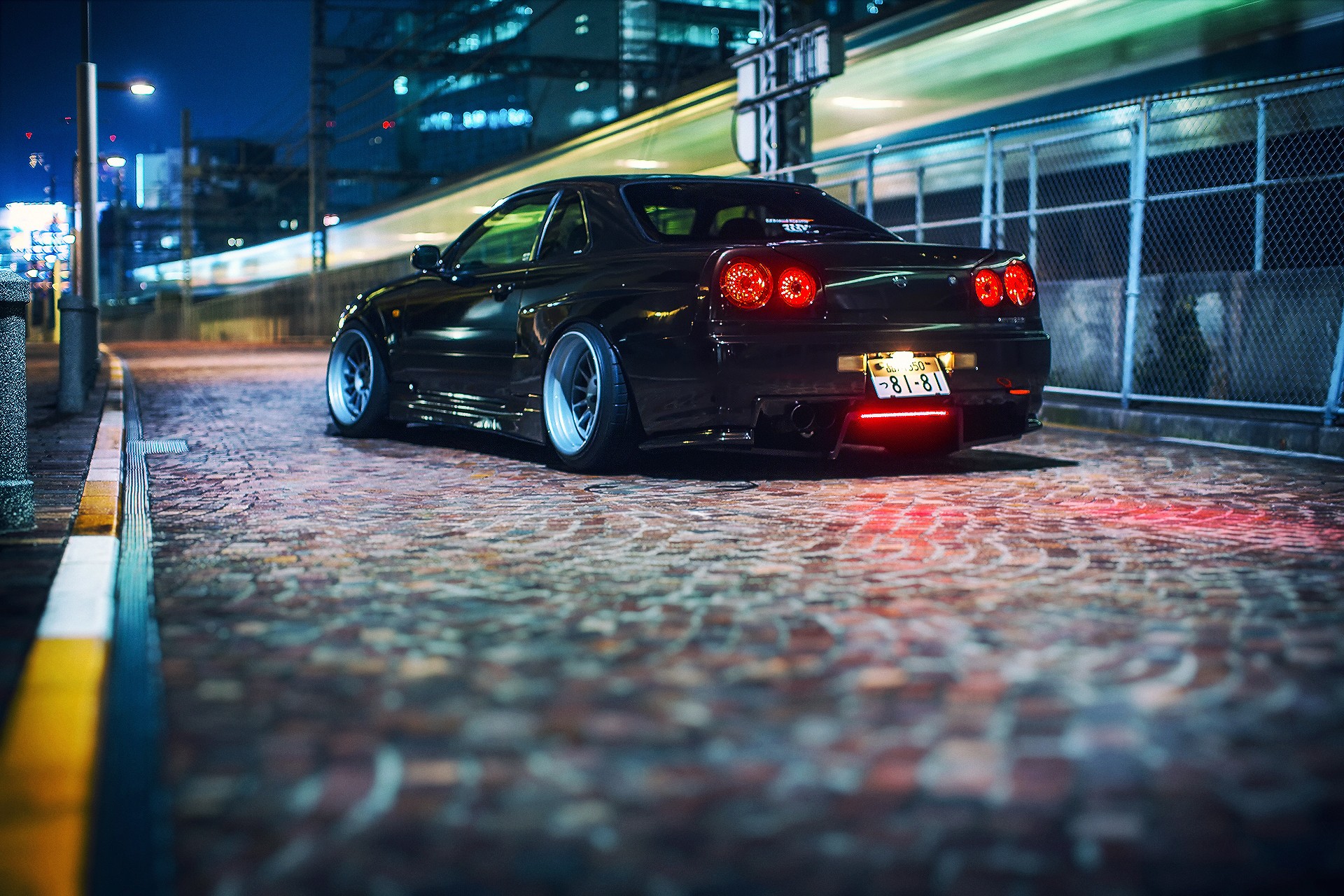 Nissan Skyline GT-R R34 parked on a cobblestone street at night HD Wallpaper