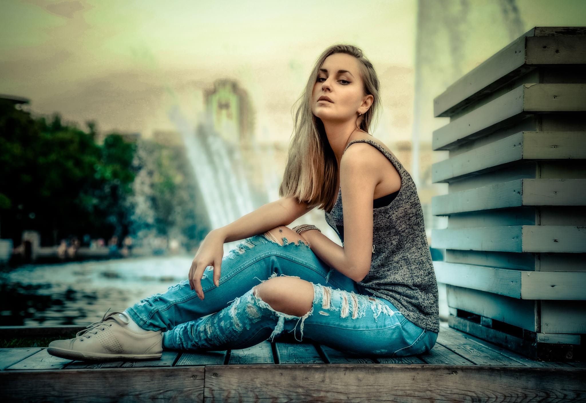 Woman in torn jeans sitting by a fountain HD Wallpaper