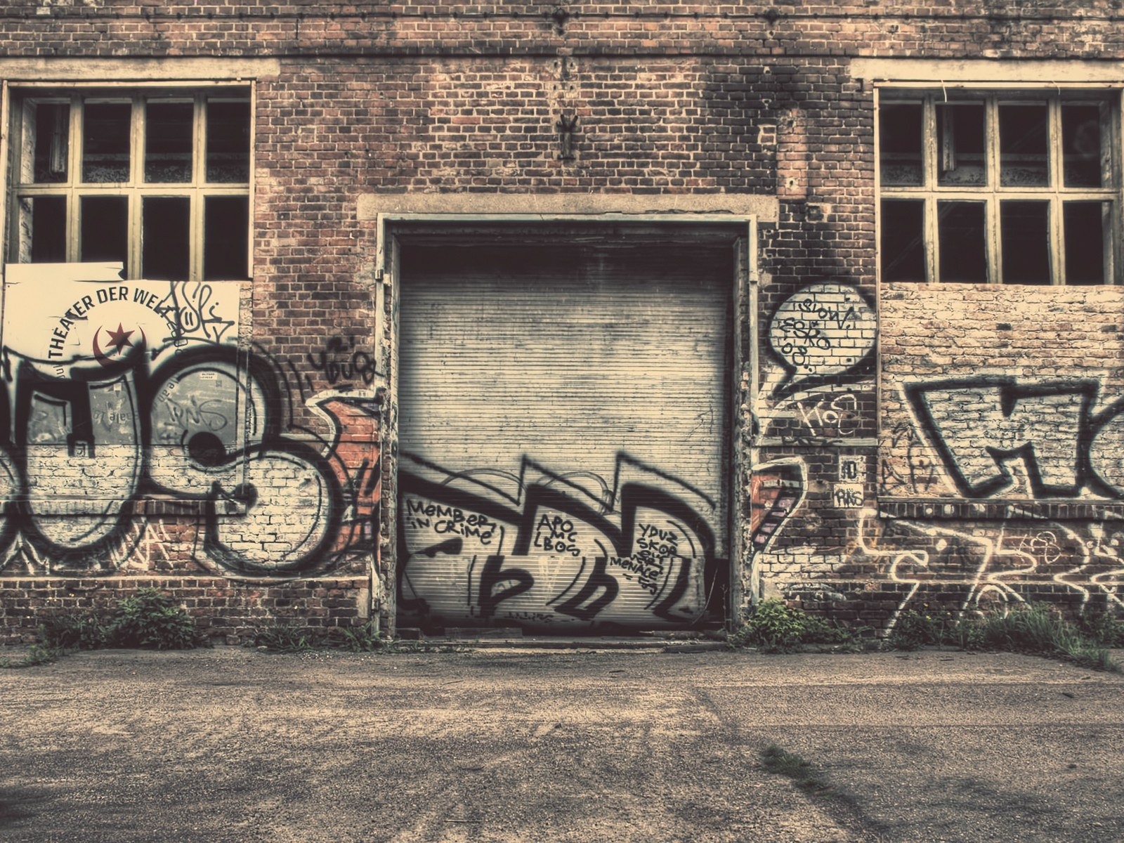 Graffiti on an abandoned brick building with a garage door HD Wallpaper