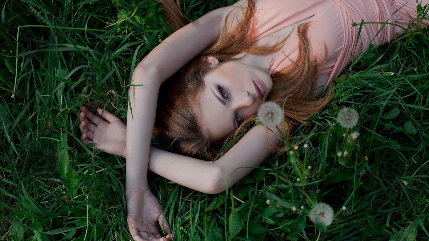 Woman lying in grass with dandelions HD Wallpaper