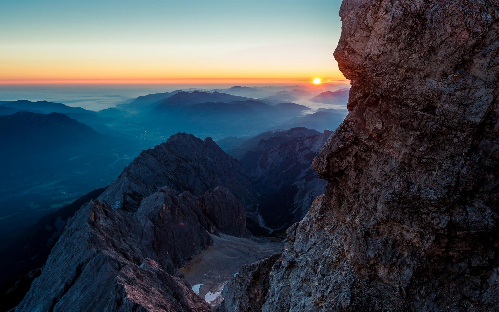 Sunrise over misty mountains from a rocky cliff HD Wallpaper