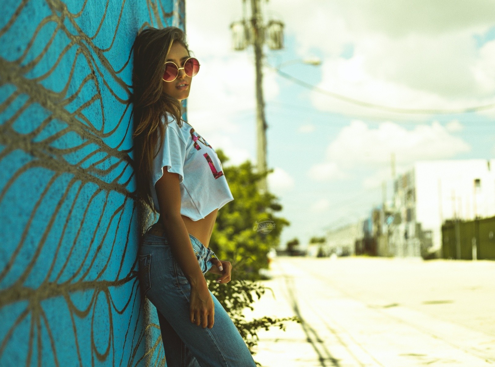 Woman in jeans and crop top leaning against a graffiti wall HD Wallpaper