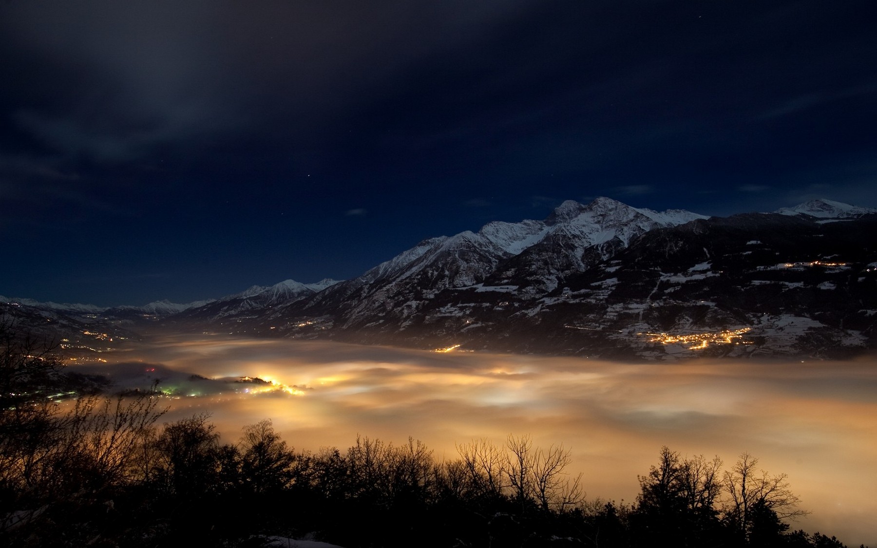 Snow-capped mountains over a misty valley at night HD Wallpaper