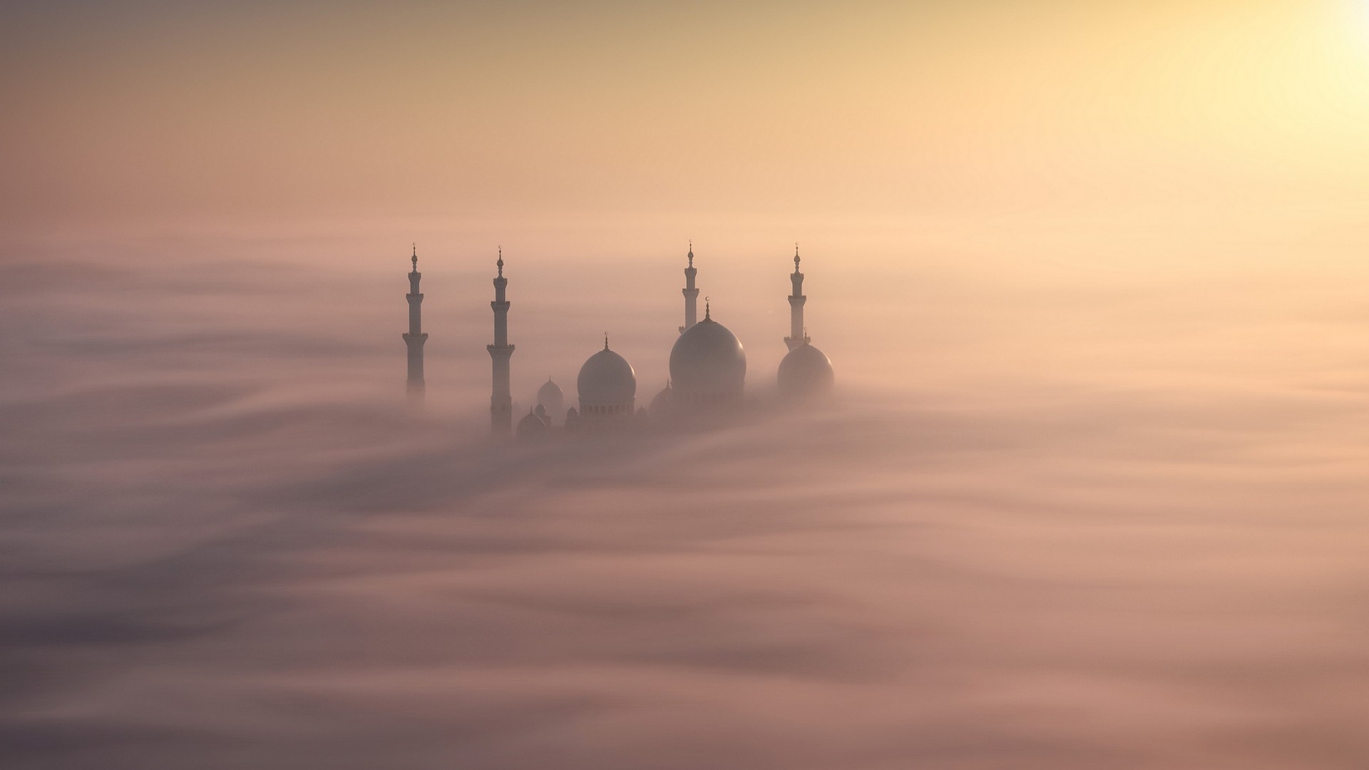 Mosque minarets and domes emerging from fog at sunrise HD Wallpaper