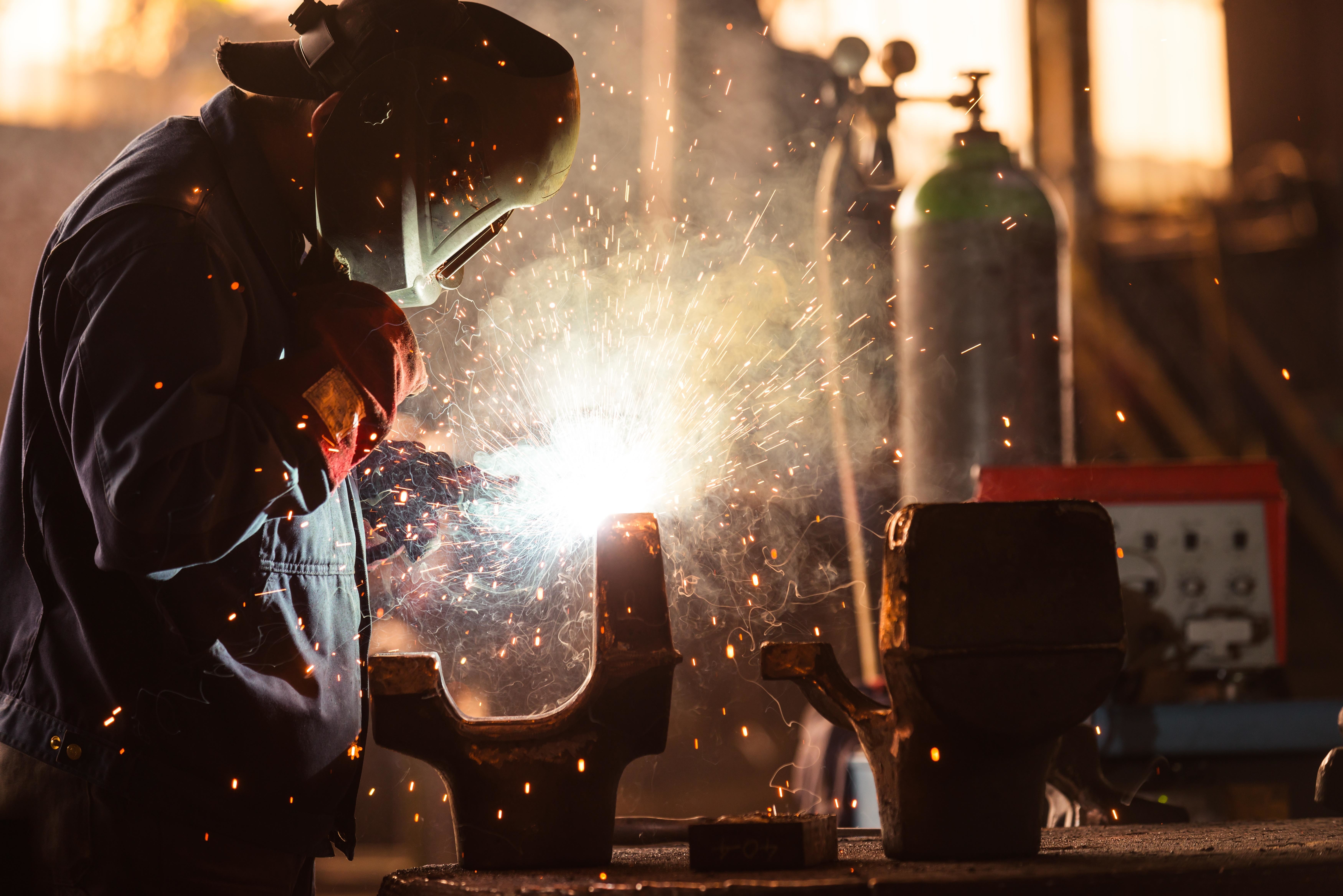 Man welding metal with sparks flying HD Wallpaper
