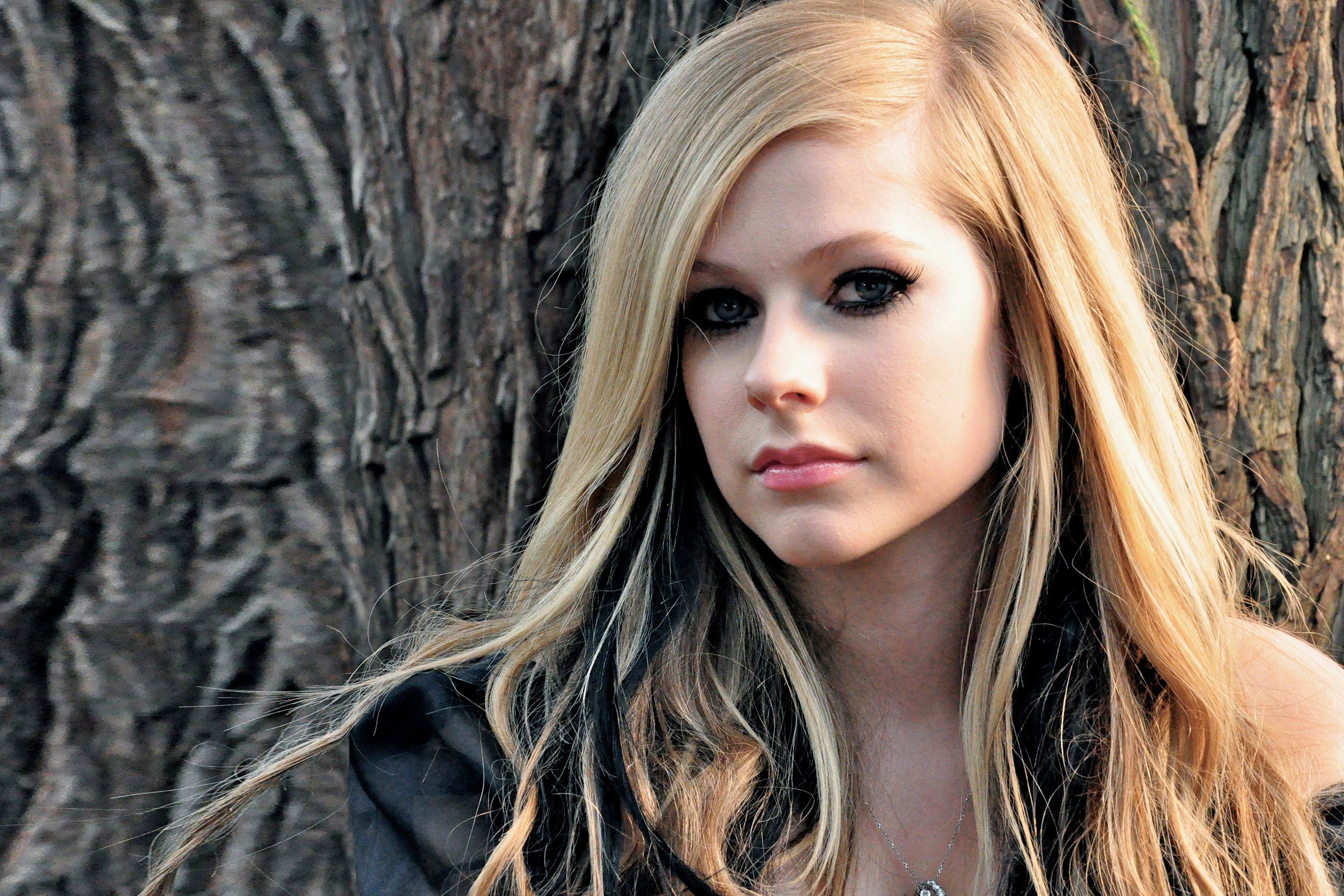 Avril Lavigne leaning against a tree HD Wallpaper