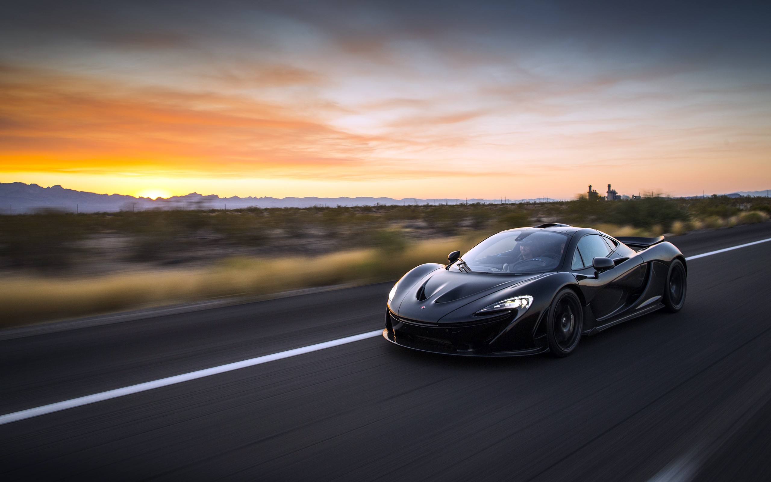 Black McLaren P1 driving on a desert road at sunset HD Wallpaper
