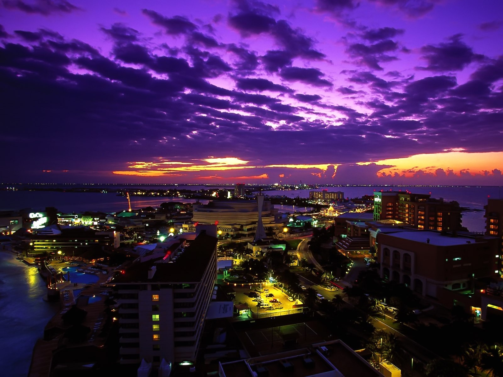 Cityscape at dusk with purple clouds over the ocean HD Wallpaper