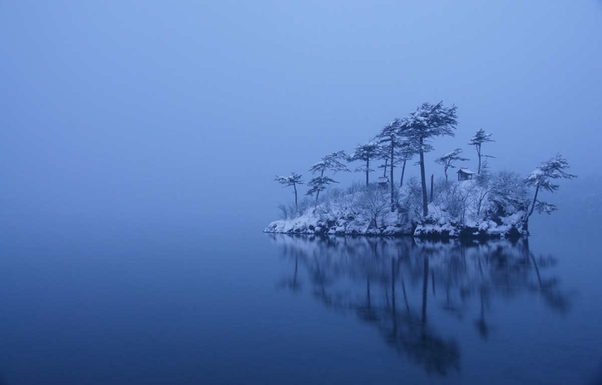Snowy island with trees and cabins in a misty lake in Japan HD Wallpaper