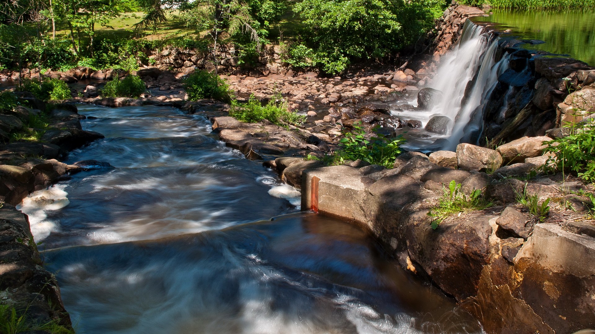 Waterfall and stream in a rocky, wooded area HD Wallpaper