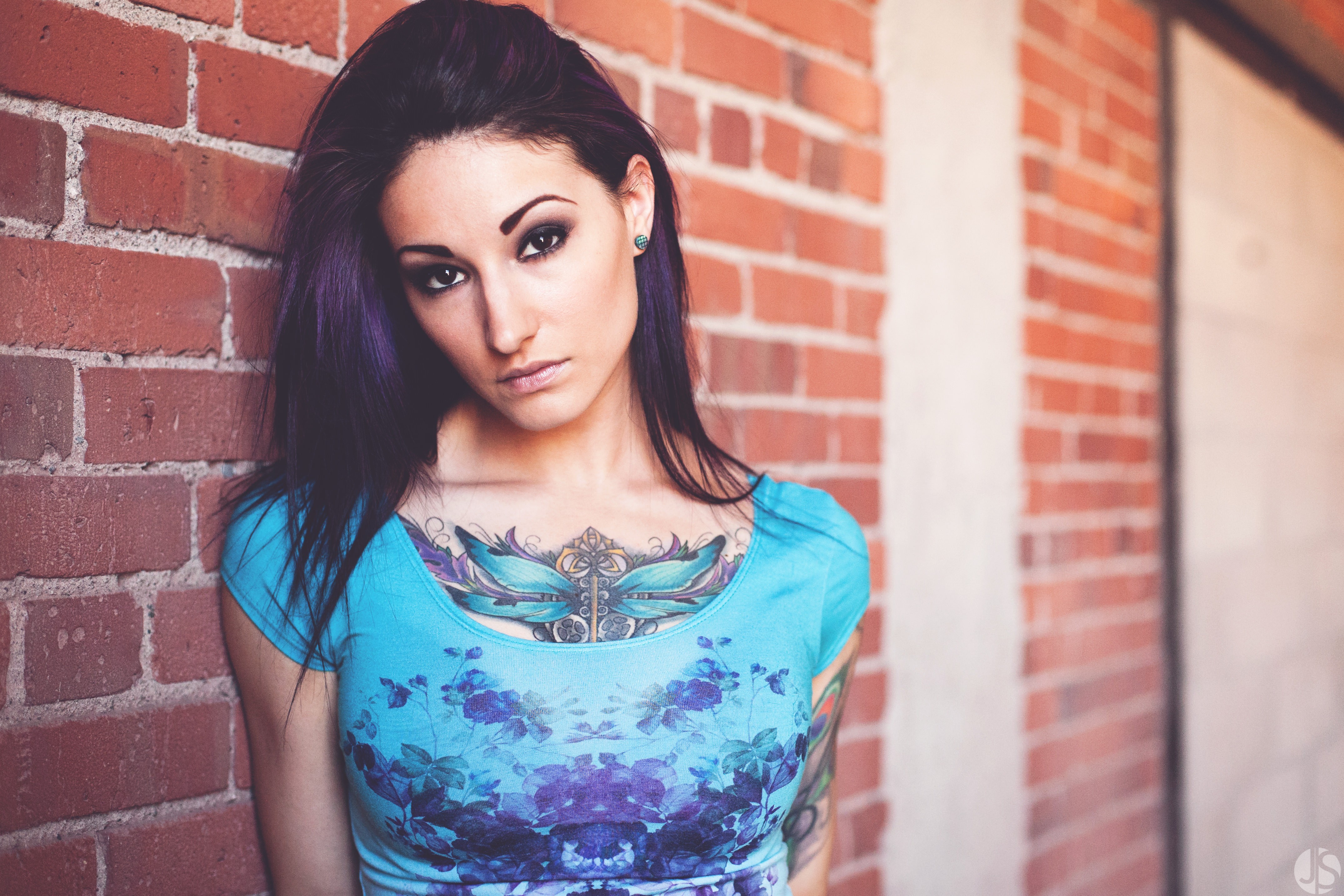 Woman with tattoos leaning against a brick wall HD Wallpaper