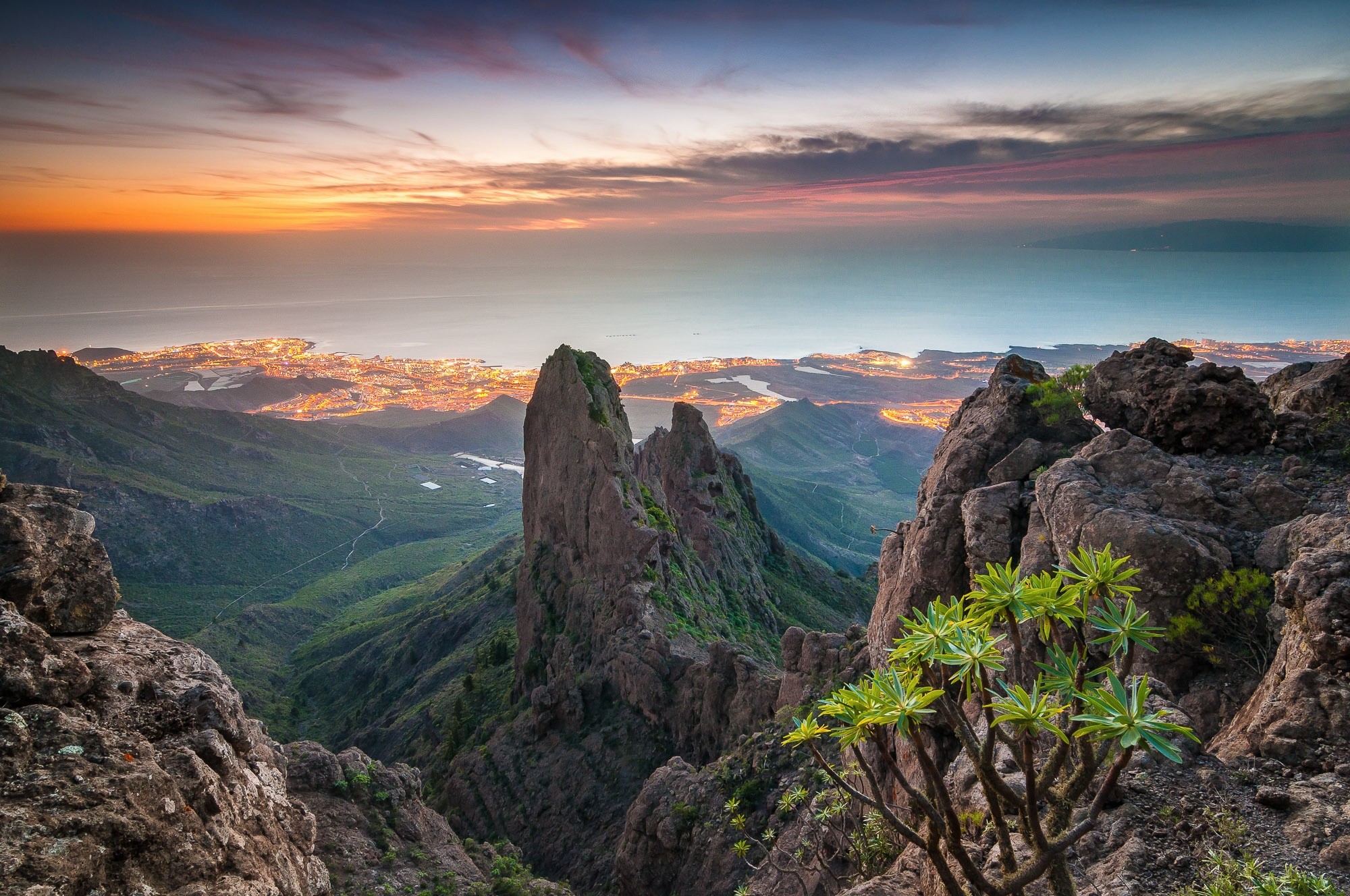 Mountain peaks overlooking a city at sunset HD Wallpaper