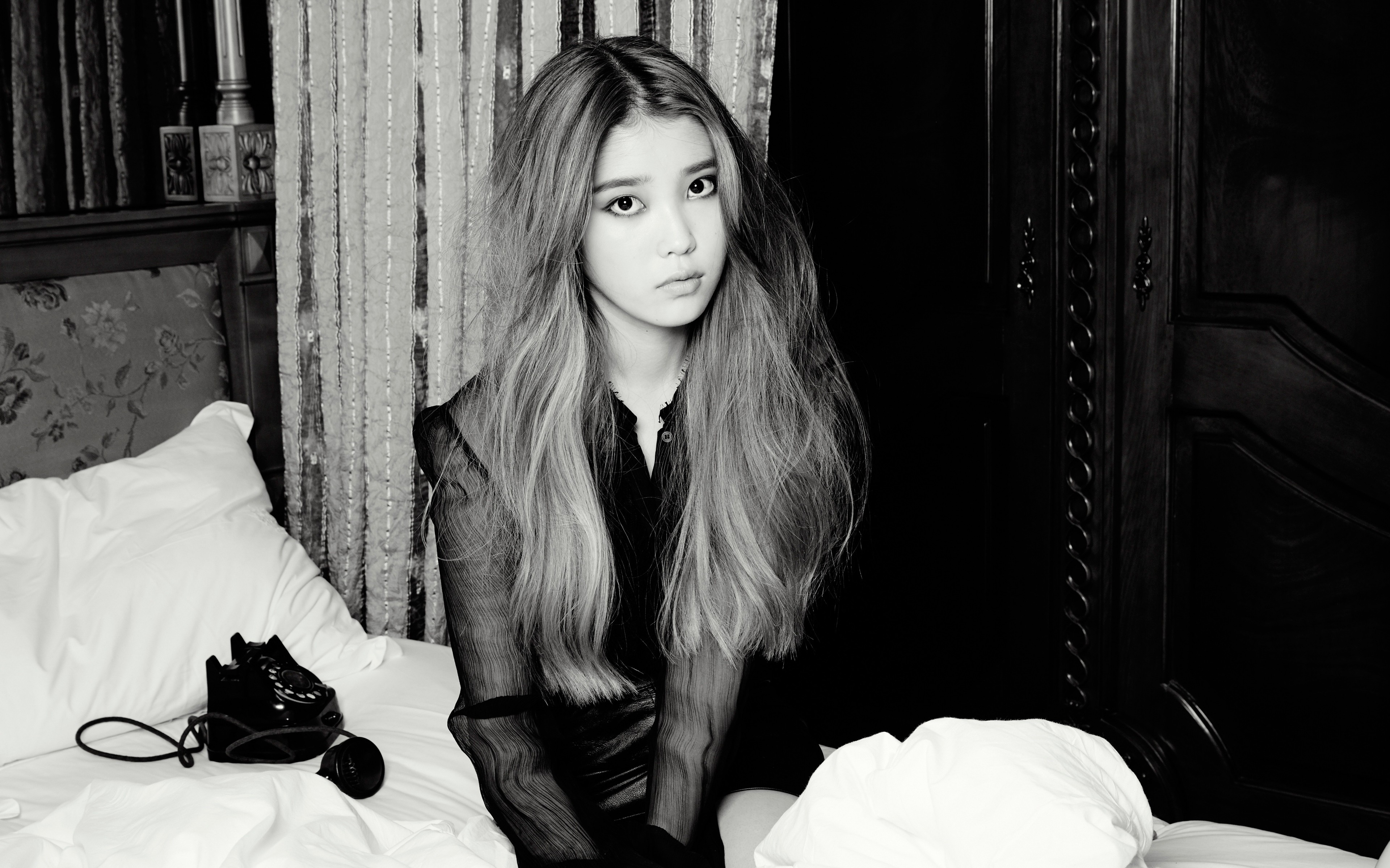 IU sitting on a bed with a vintage phone HD Wallpaper