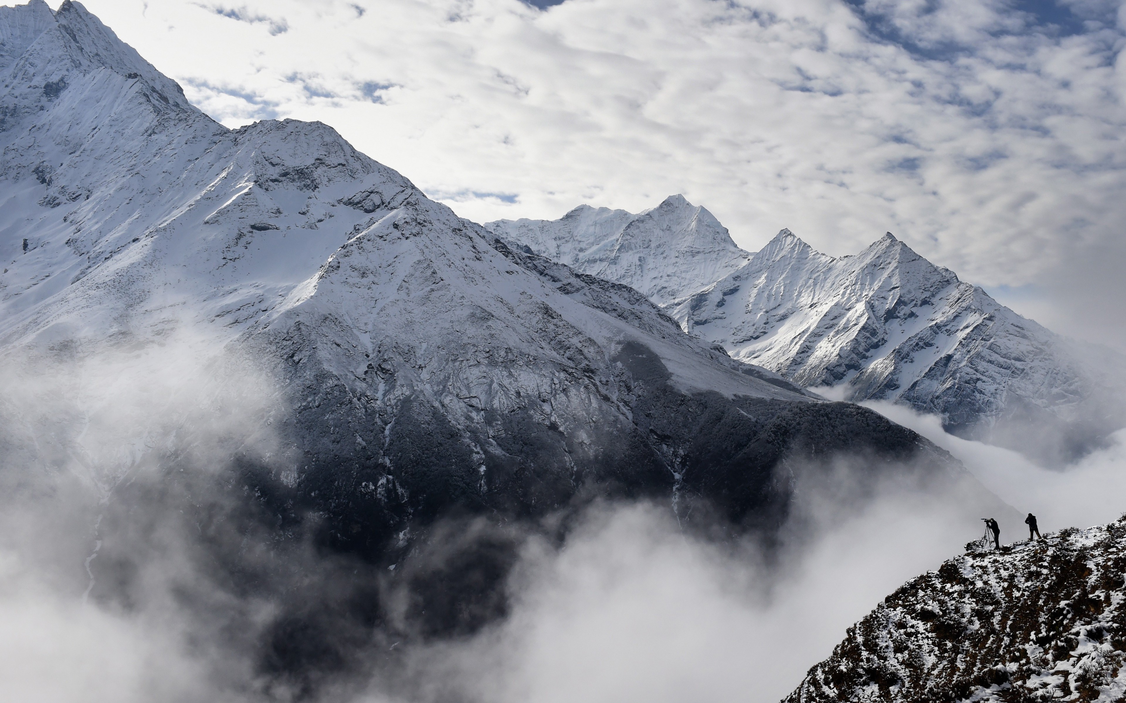 Two hikers on a snowy mountain ridge with clouds HD Wallpaper