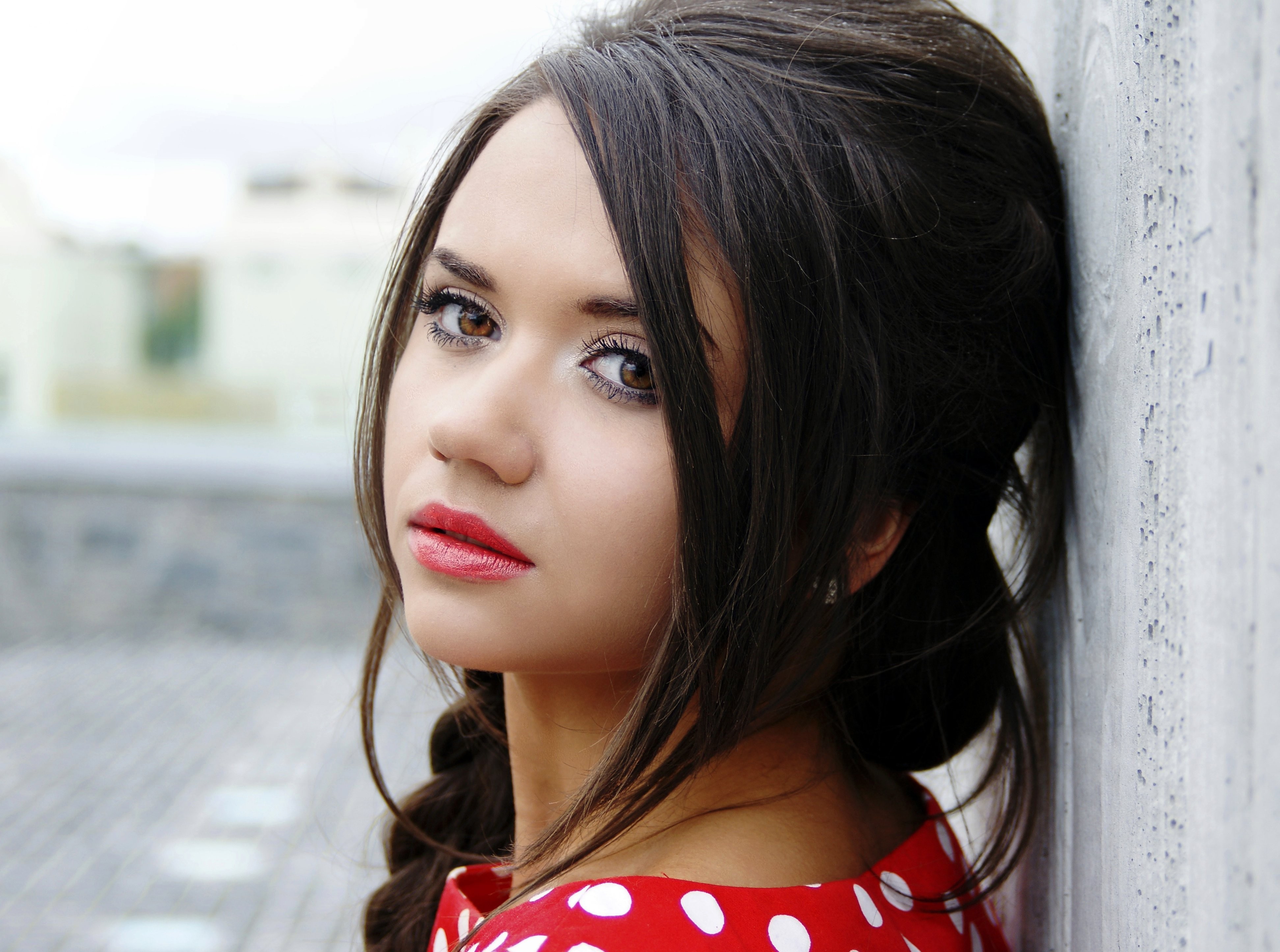 Woman with hazel eyes leaning against a wall HD Wallpaper
