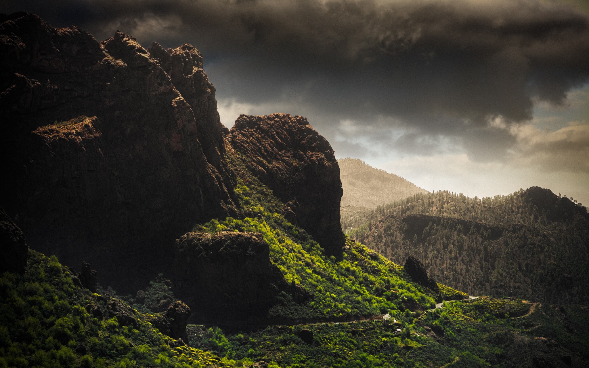 Dramatic mountain landscape with green slopes and dark clouds HD Wallpaper