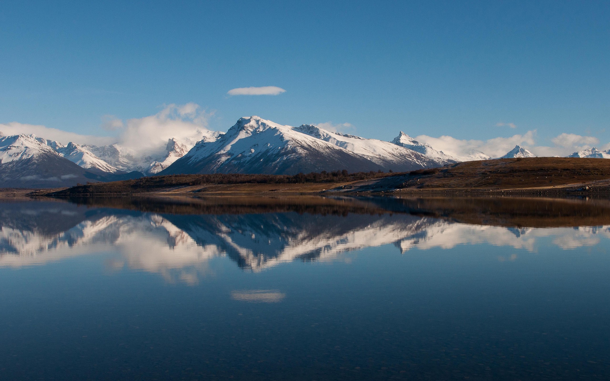 Snowy mountains reflected in a calm lake under a blue sky HD Wallpaper