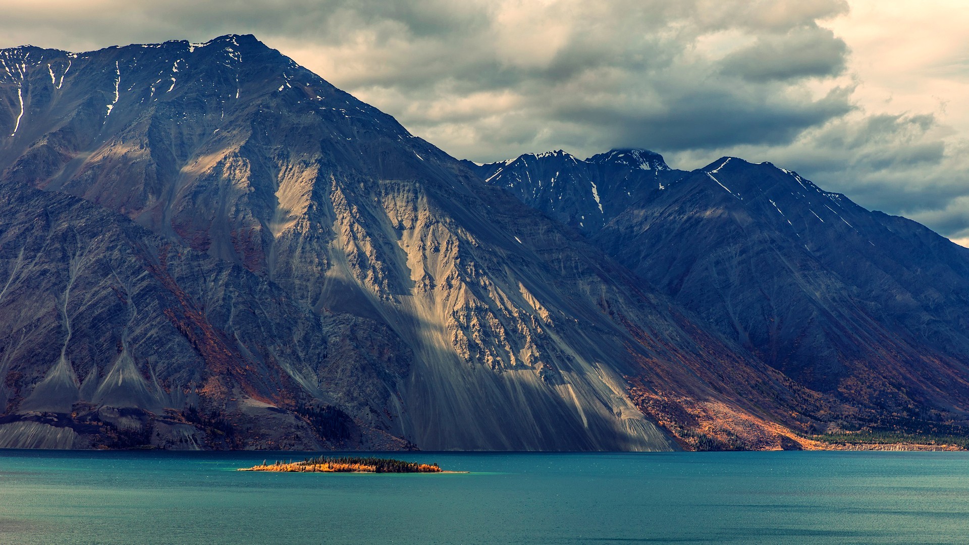 Mountains overlooking a turquoise lake with an island HD Wallpaper