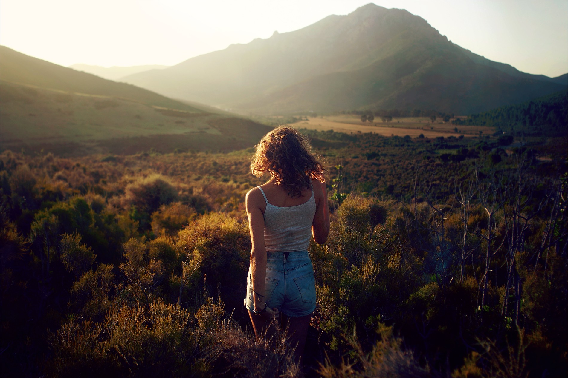 Woman in denim shorts and tank top in mountains HD Wallpaper