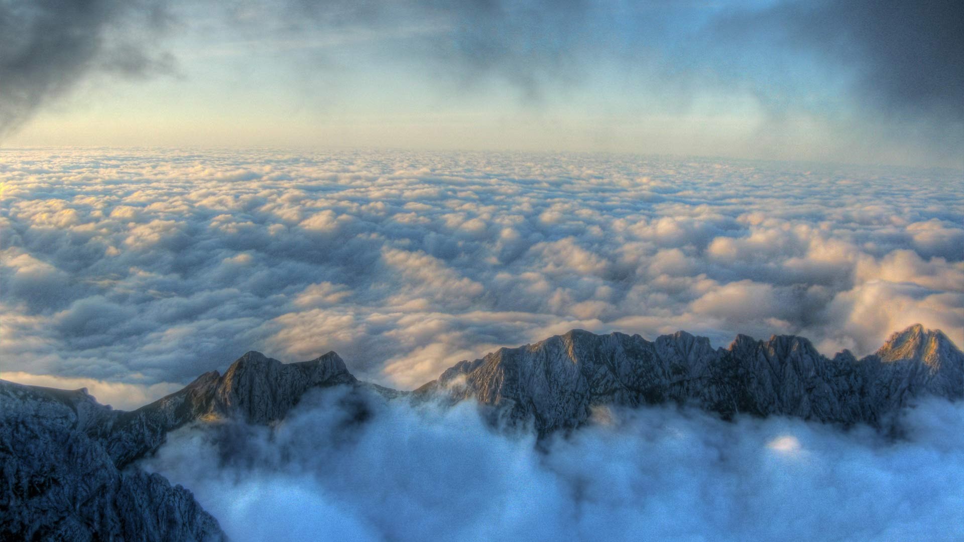 Mountain range above clouds at sunrise HD Wallpaper