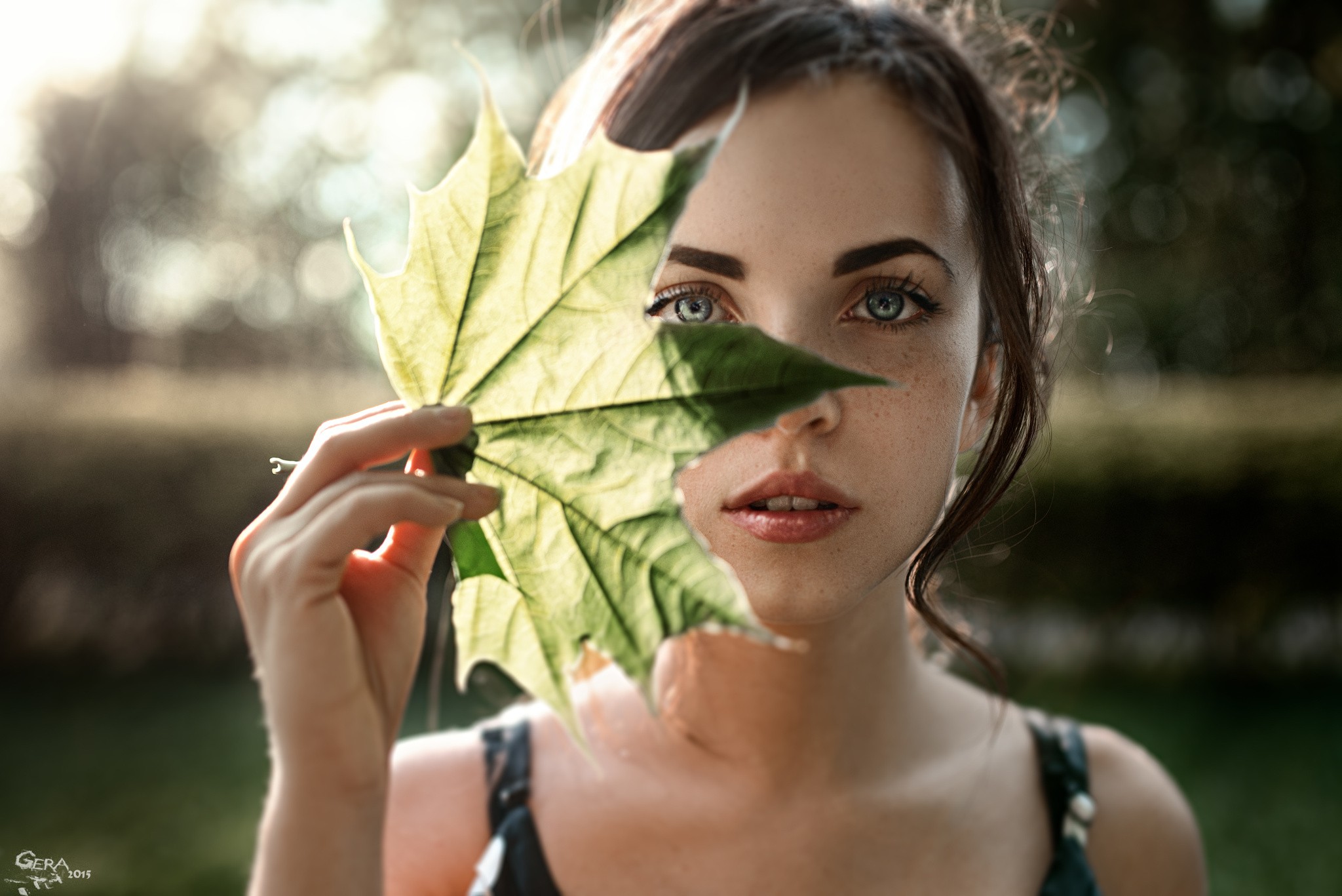 Woman holding a green leaf in front of her face HD Wallpaper