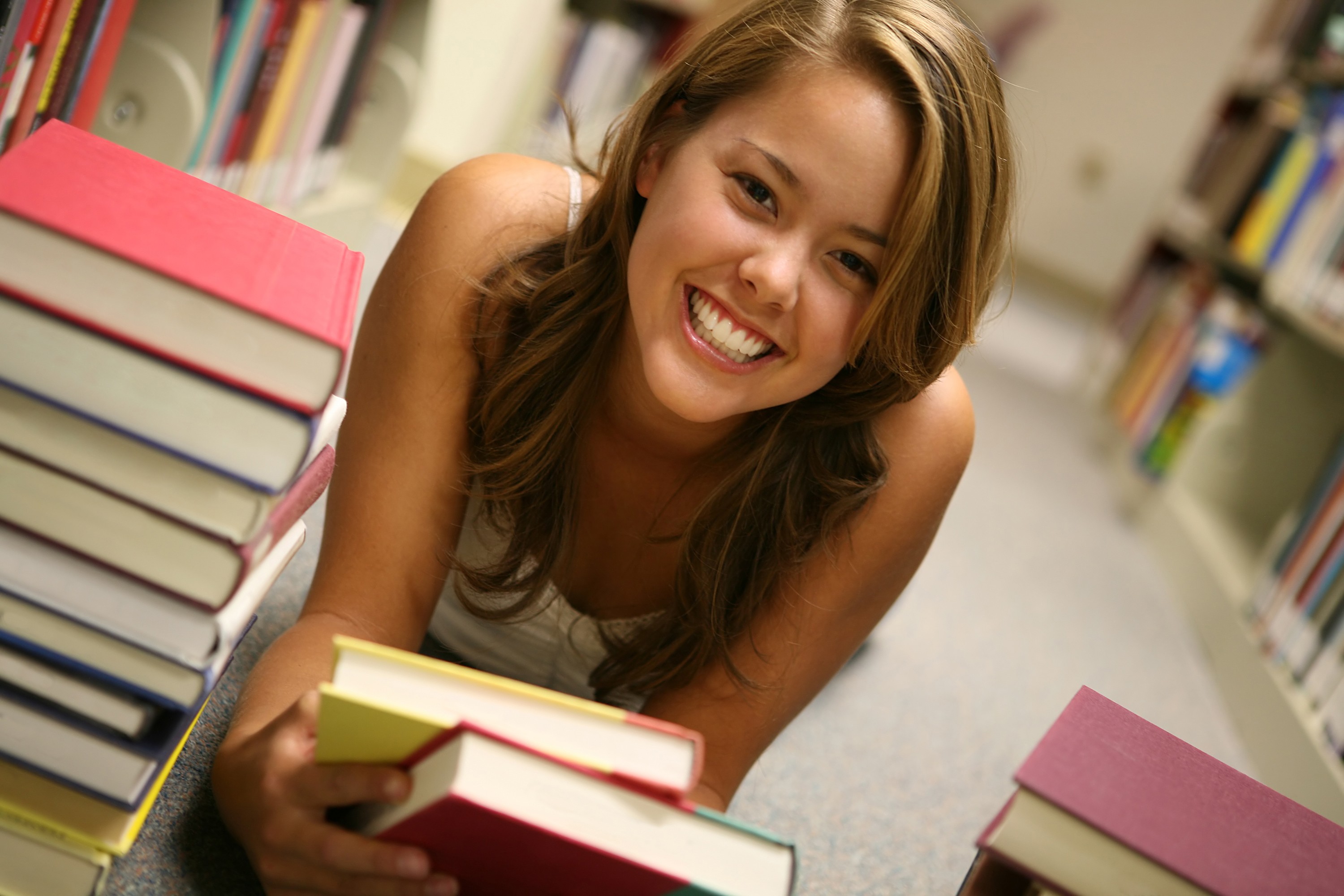 Young woman smiling in a library with books HD Wallpaper
