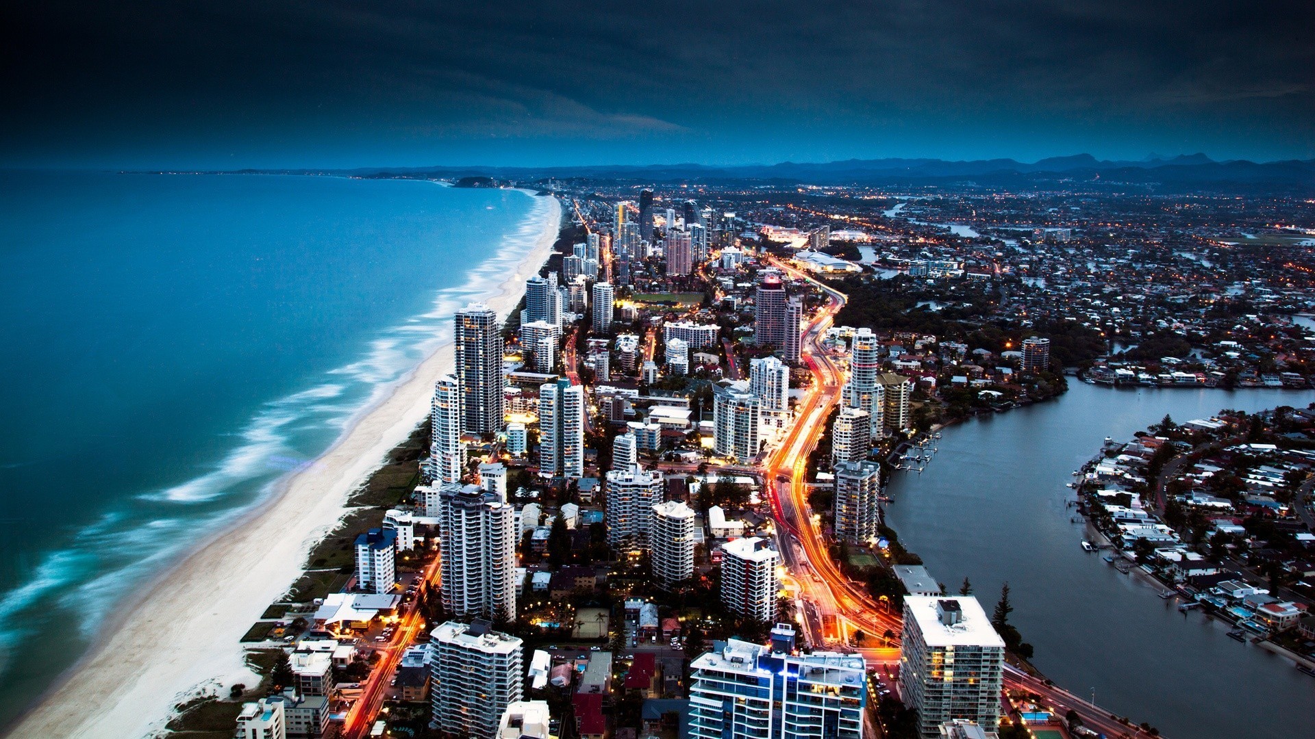 Aerial view of a coastal city at dusk HD Wallpaper