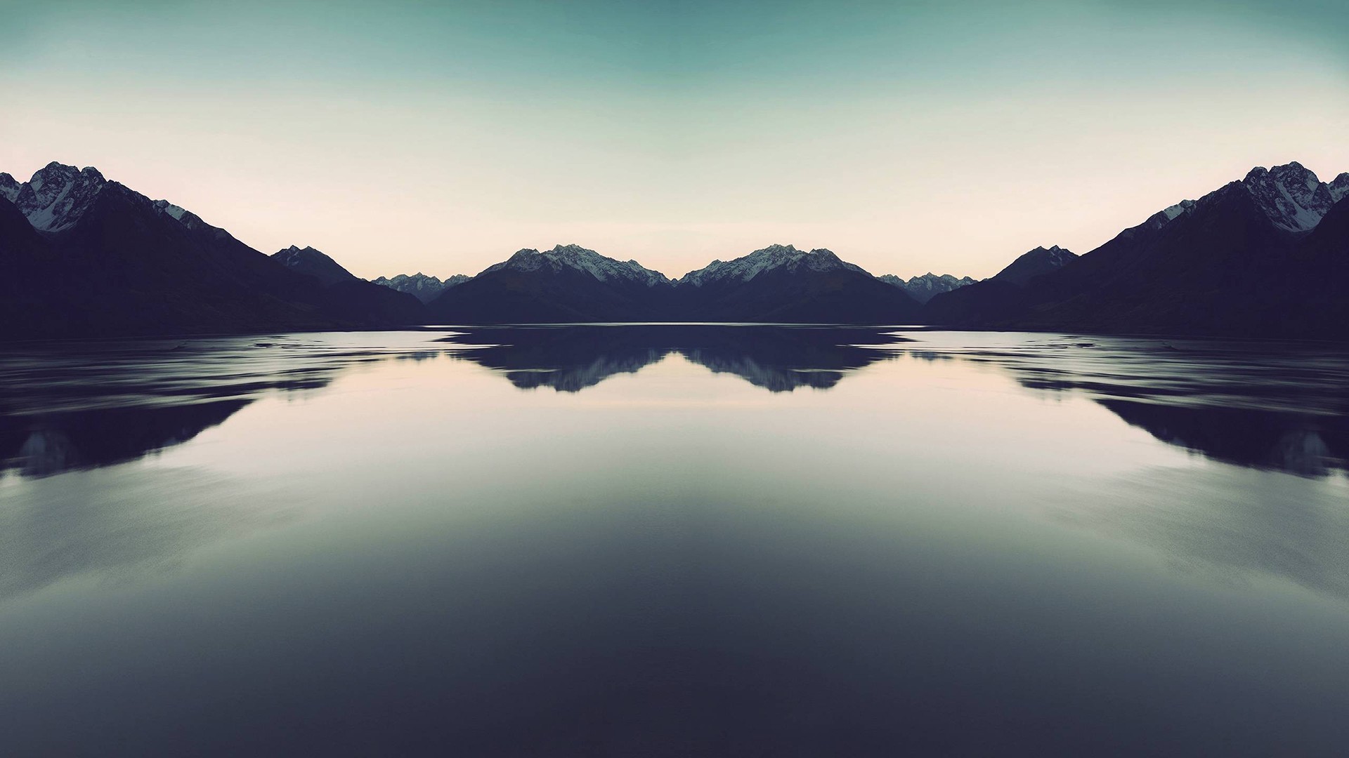 Symmetrical mountain range reflected in a calm lake at dusk HD Wallpaper