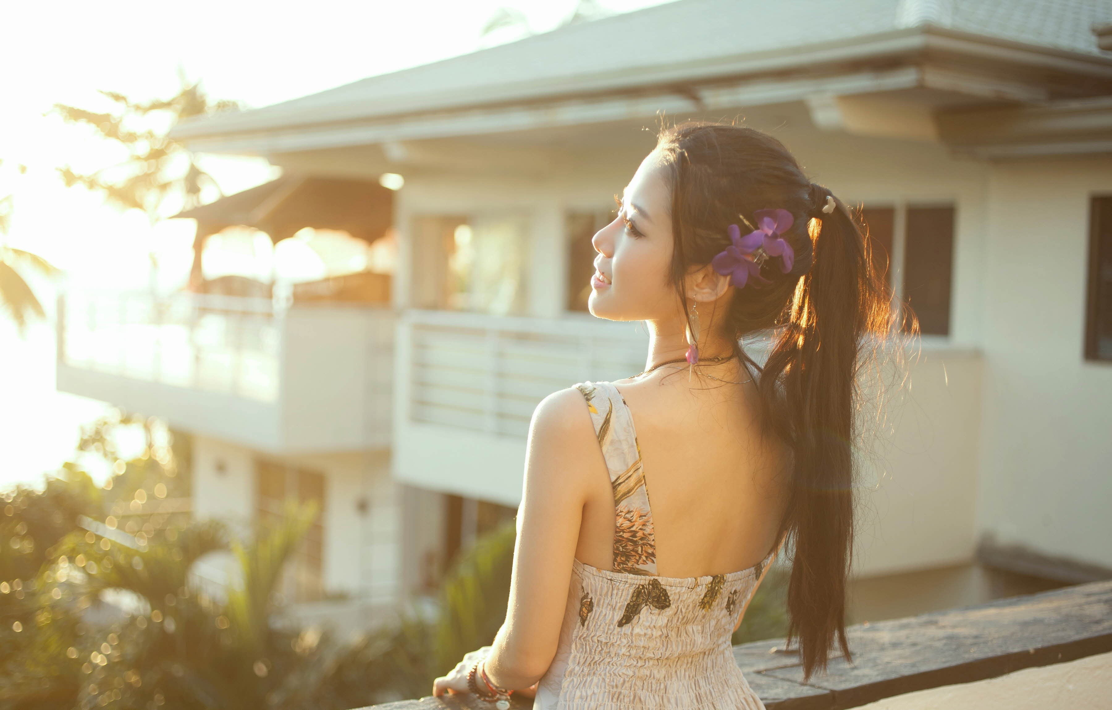 Asian woman with flower in hair on balcony HD Wallpaper