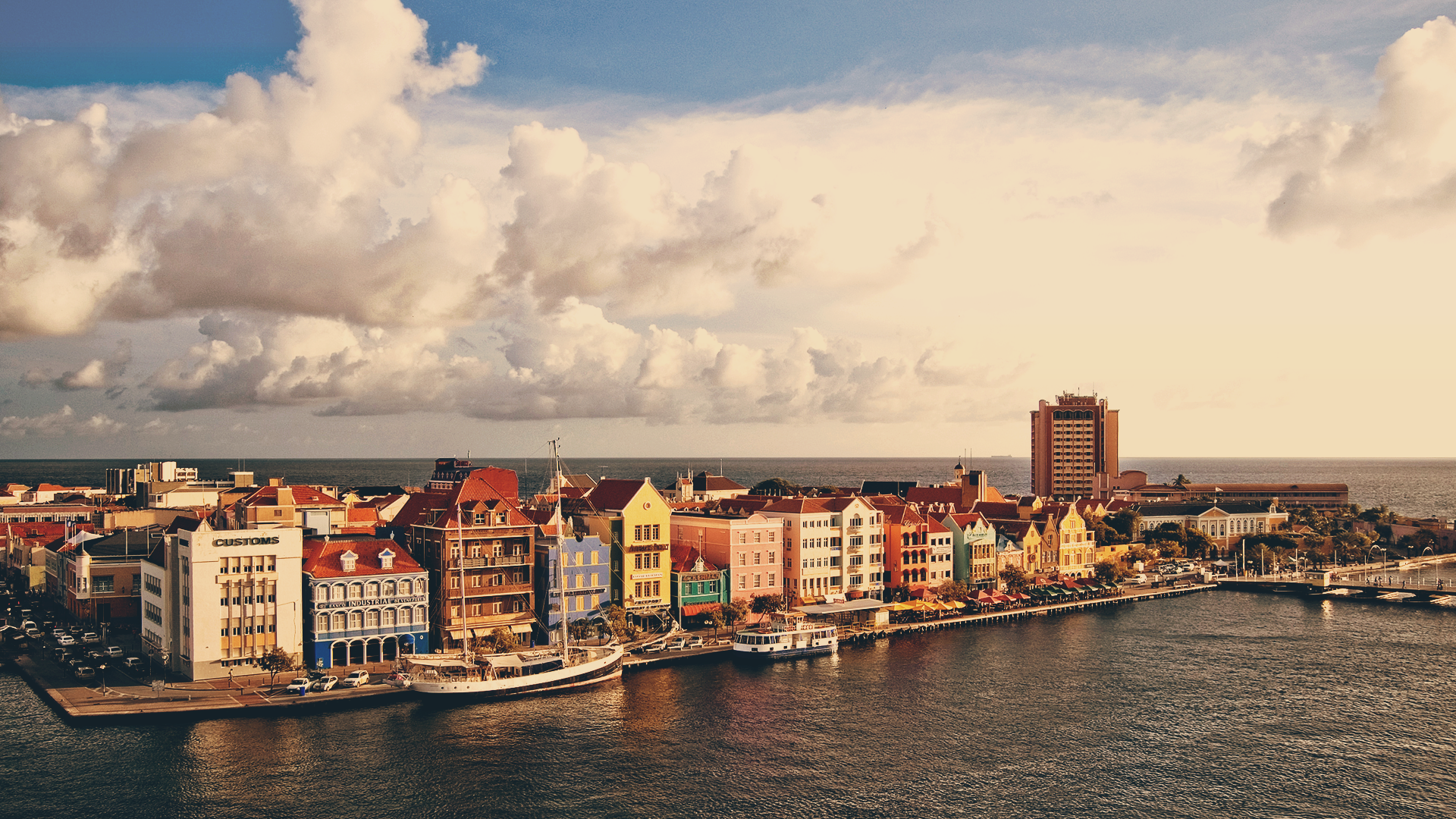 Colorful buildings along the waterfront with boats and clouds HD Wallpaper