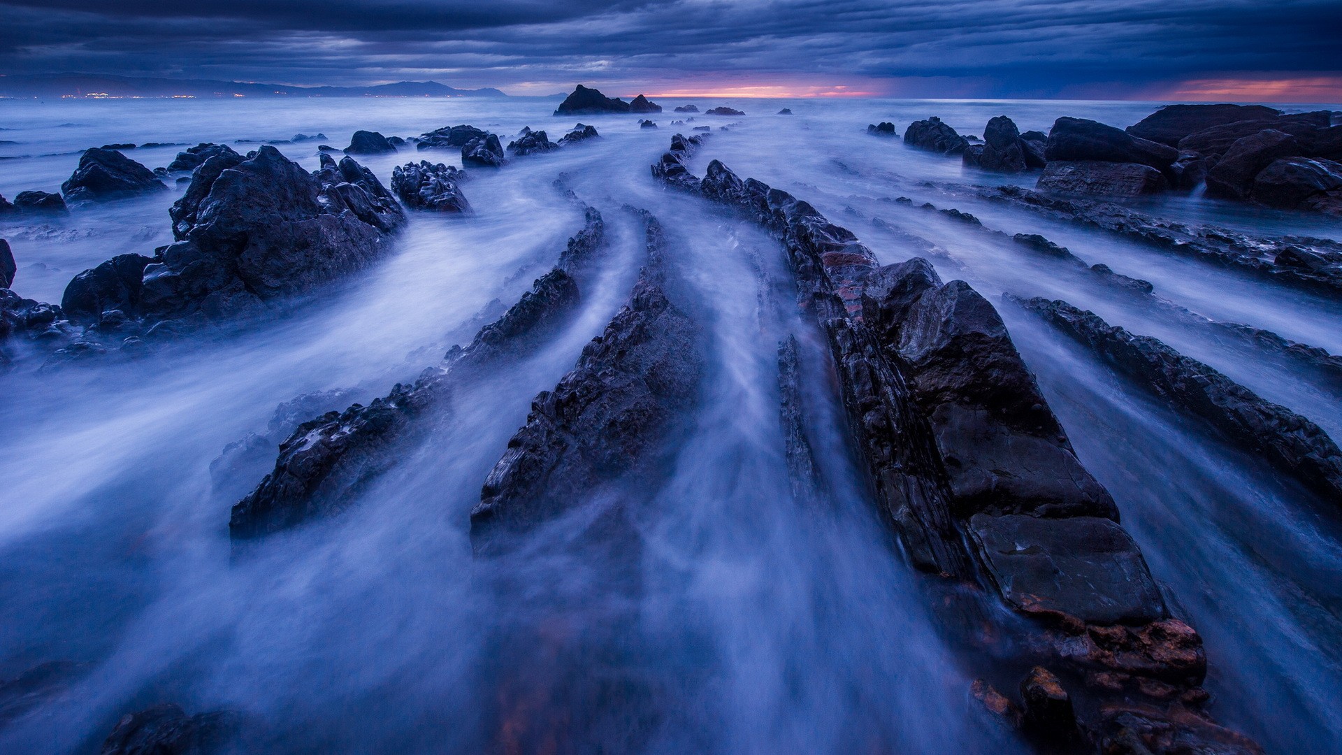 Rocky coastline with misty ocean waves at dusk HD Wallpaper