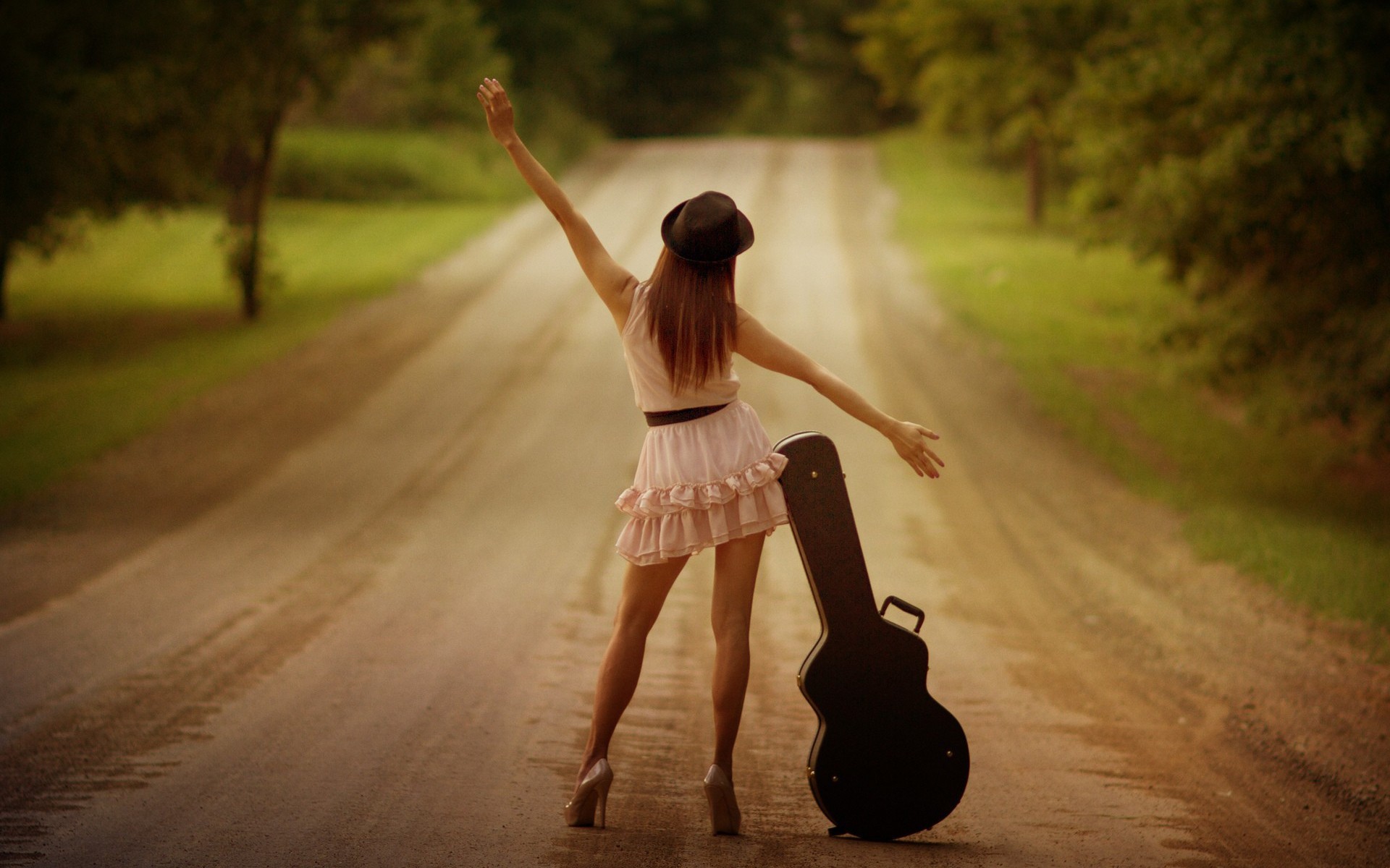 Woman with guitar case on a dirt road HD Wallpaper