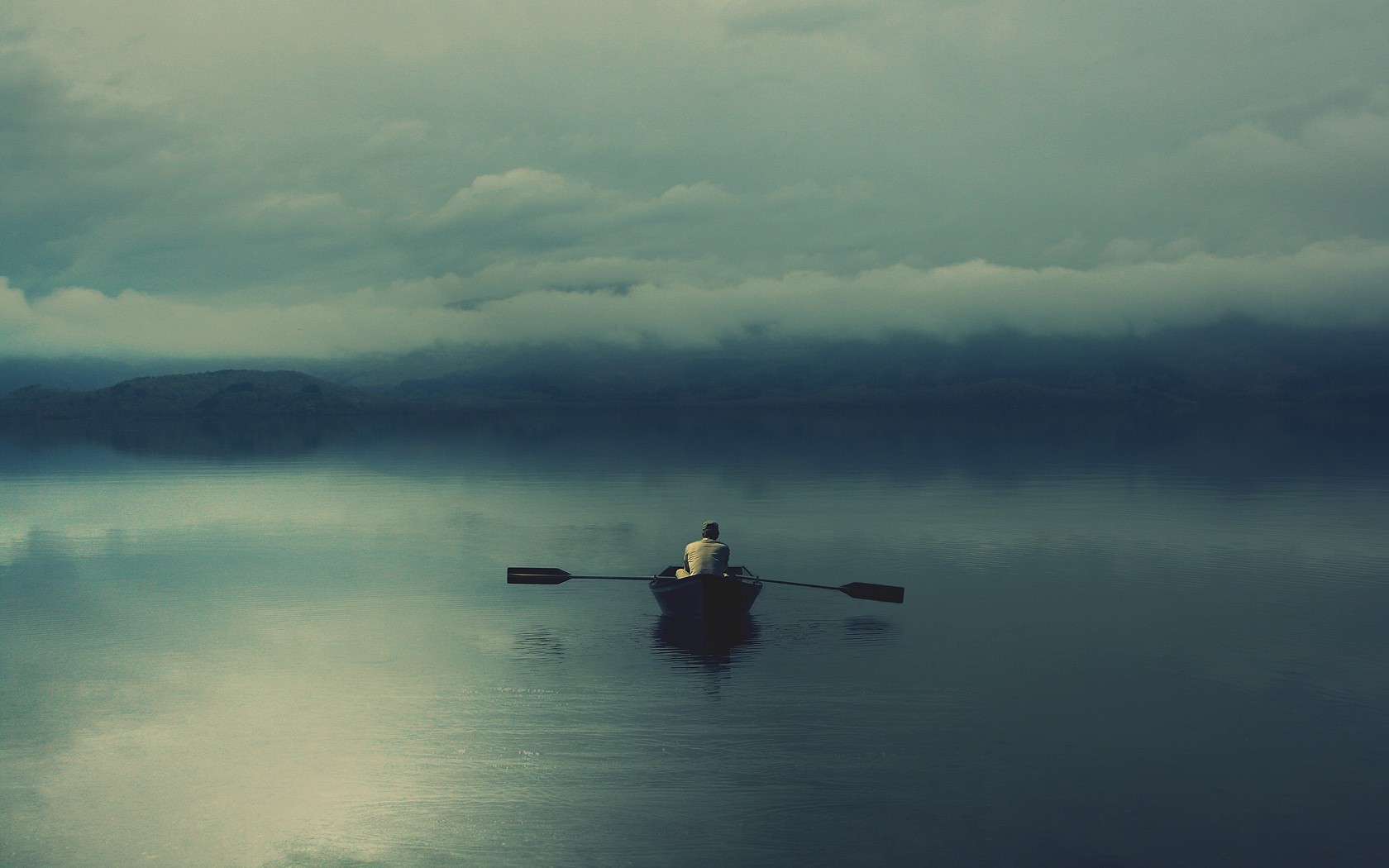 Man rowing a boat on a misty lake HD Wallpaper