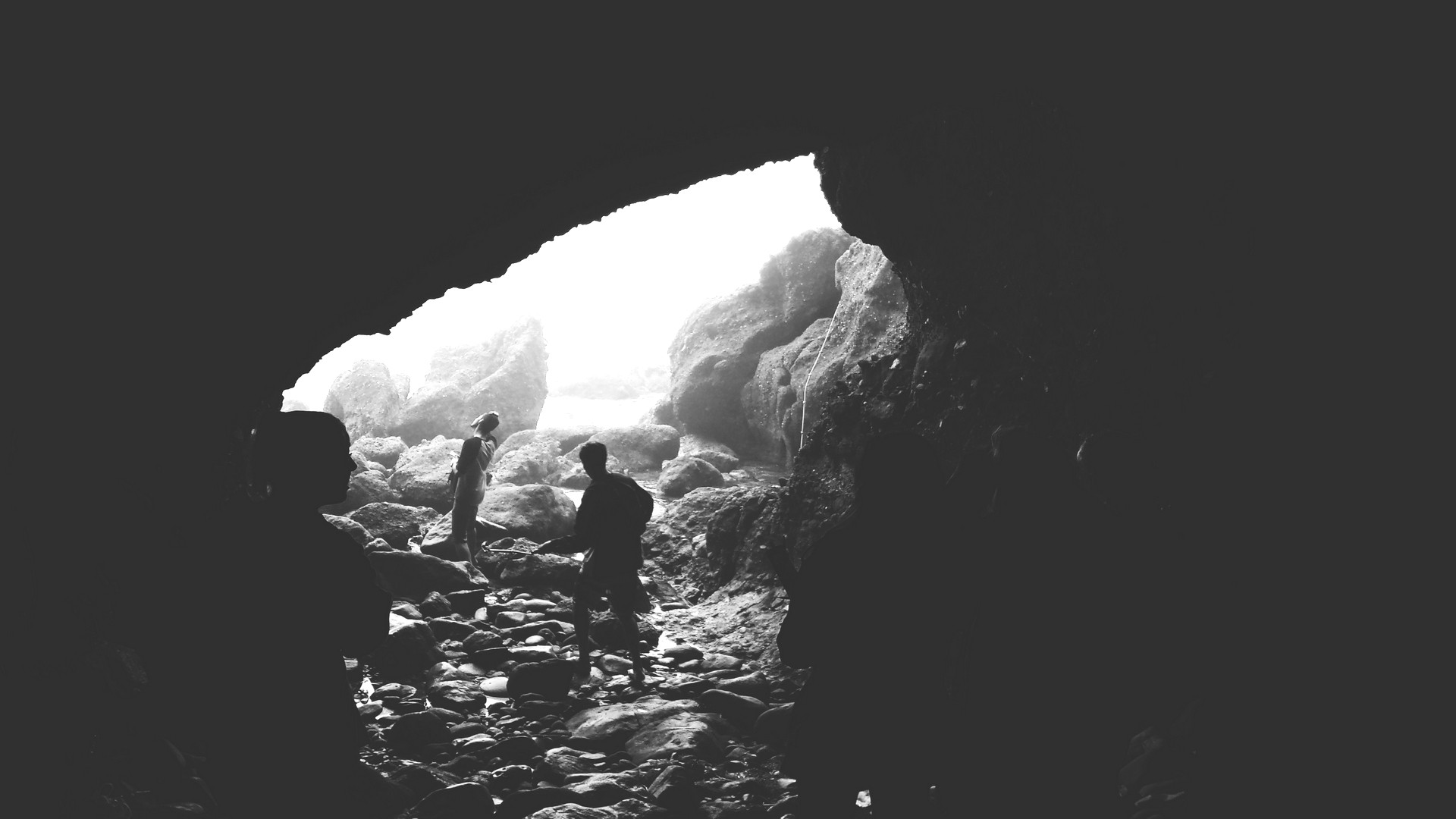 People walking through a cave entrance HD Wallpaper