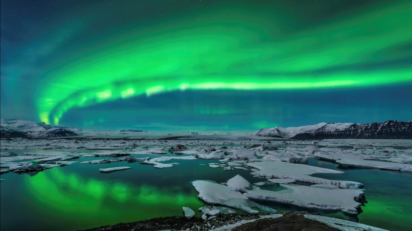 Aurora Borealis over a frozen landscape with ice and mountains HD Wallpaper