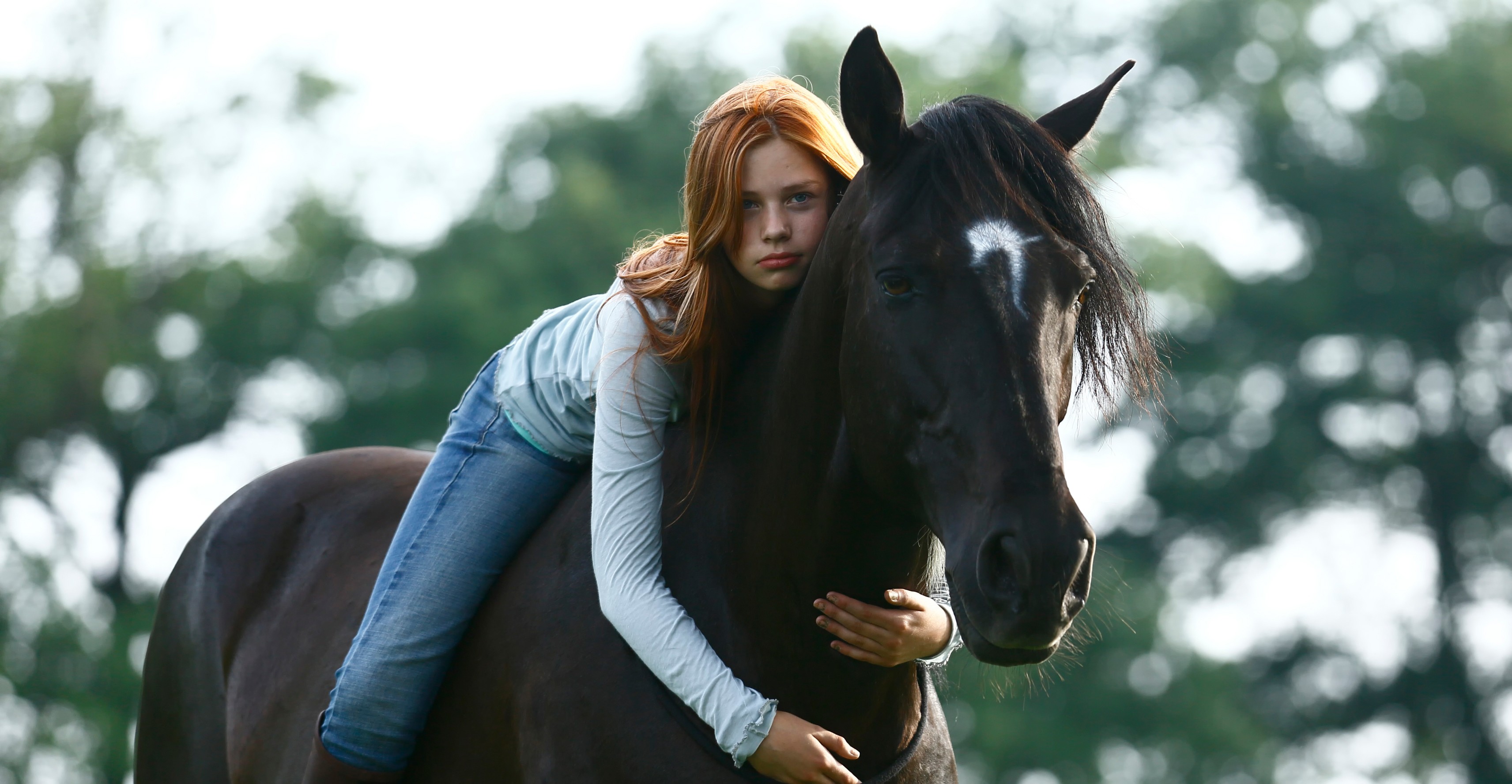 Young redhead girl hugging a black horse HD Wallpaper