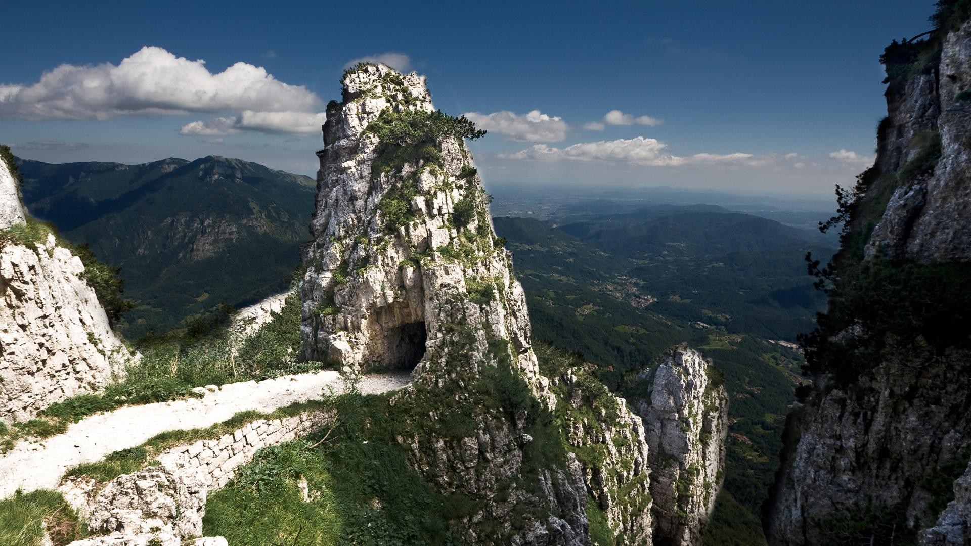Mountain path carved into a rocky cliff face HD Wallpaper
