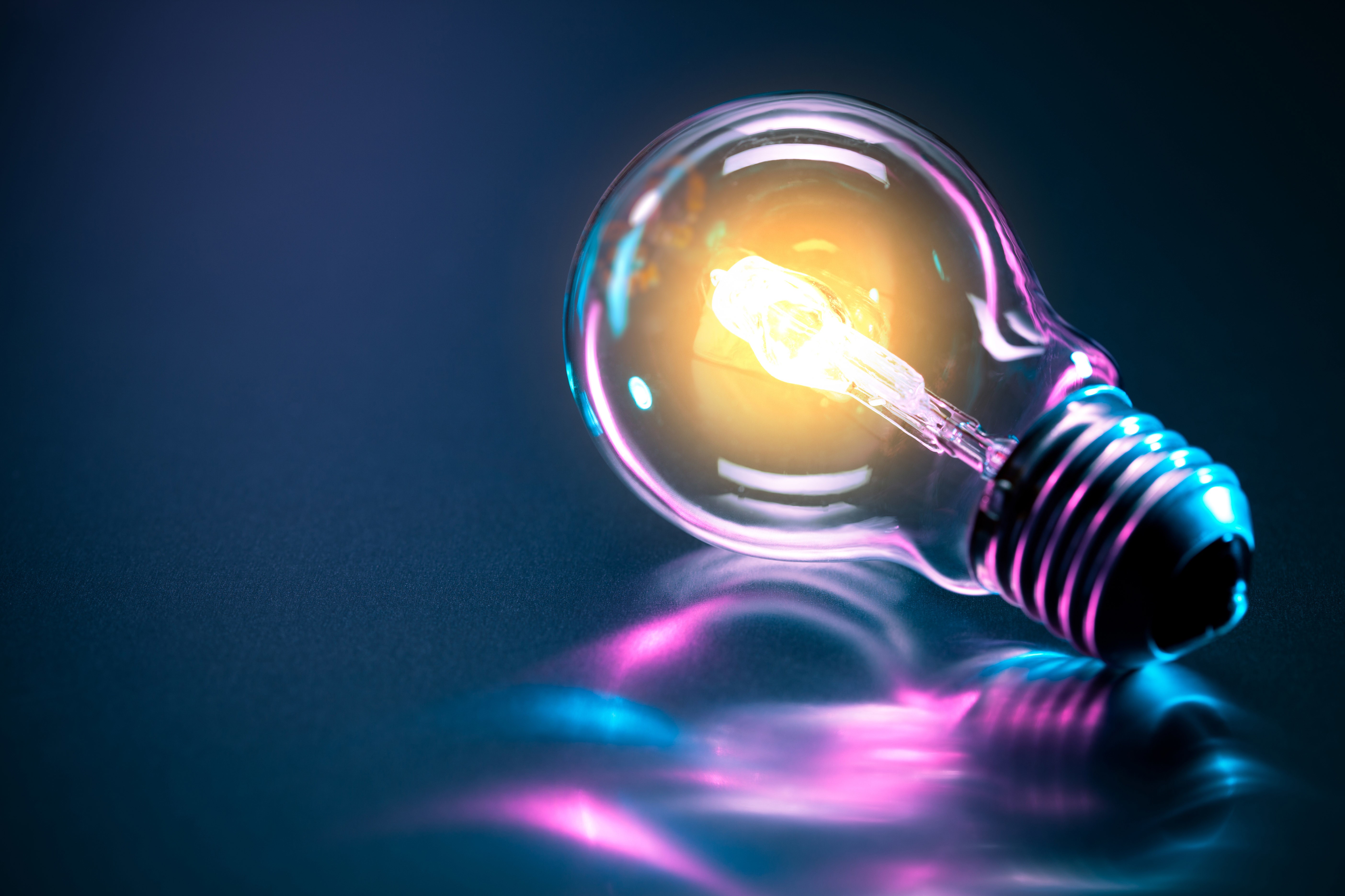 Glowing light bulb with colorful reflections HD Wallpaper