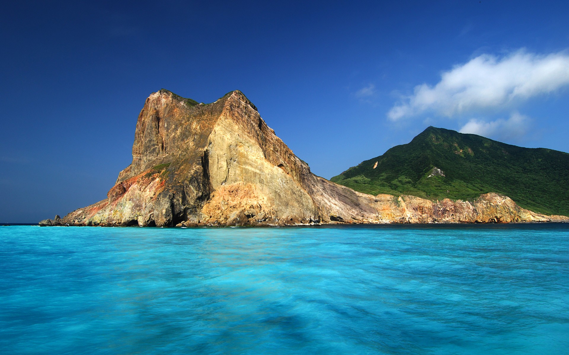 Rocky island coast with turquoise water and blue sky HD Wallpaper