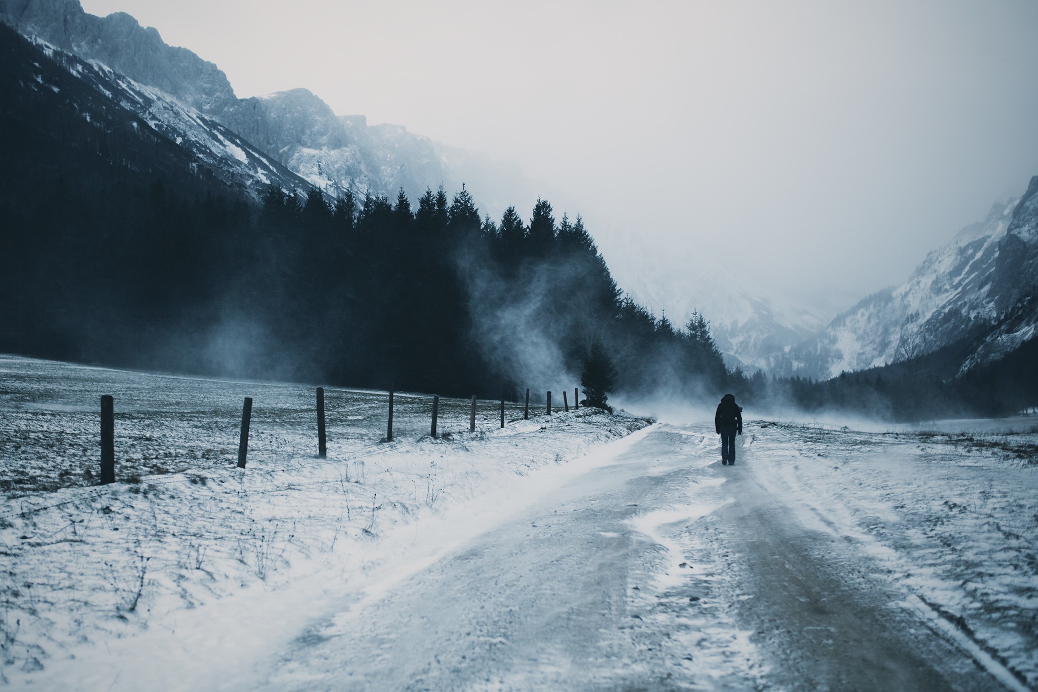 Person walking on a snowy road in the mountains HD Wallpaper