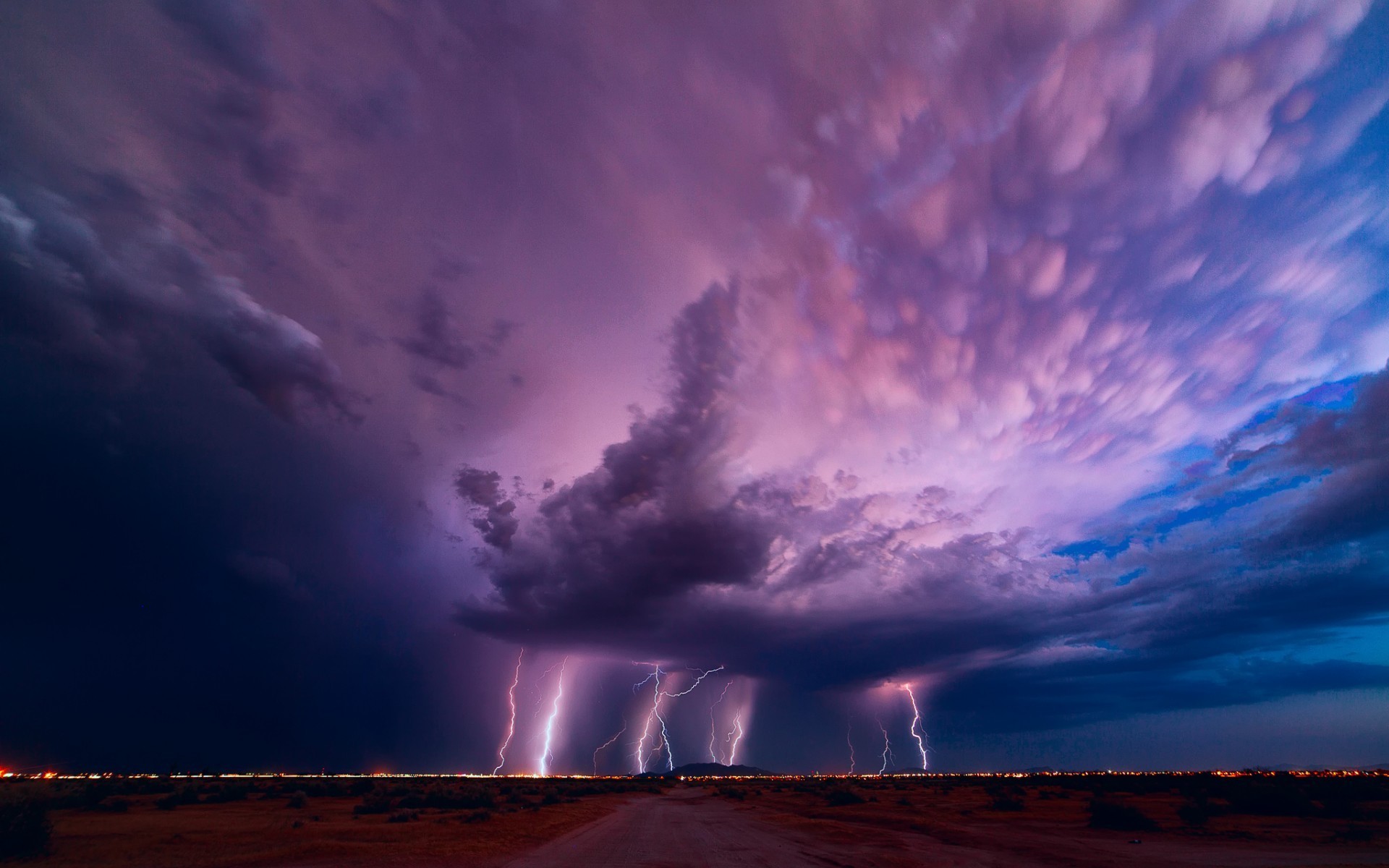 Lightning strikes over a desert landscape during a storm HD Wallpaper
