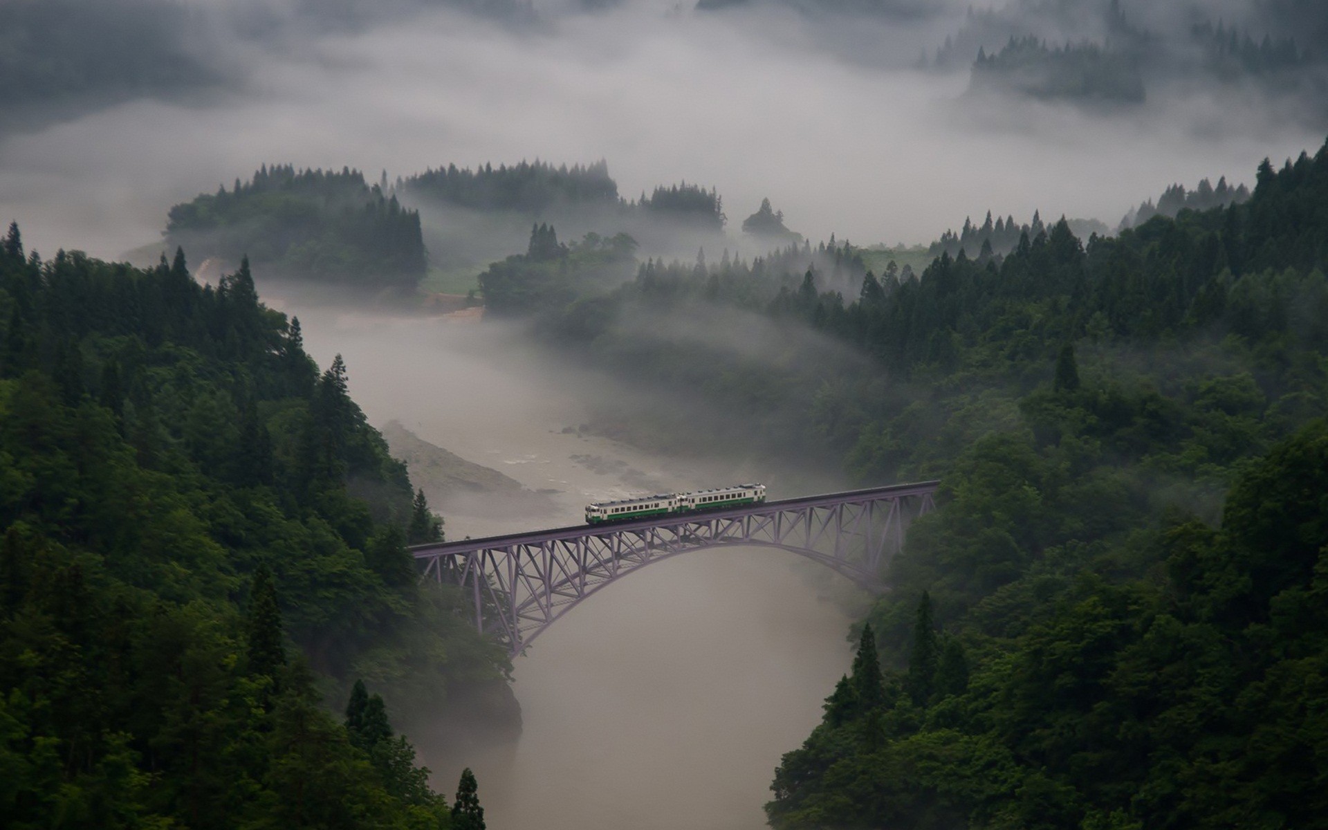Train crossing a bridge over a misty river valley HD Wallpaper
